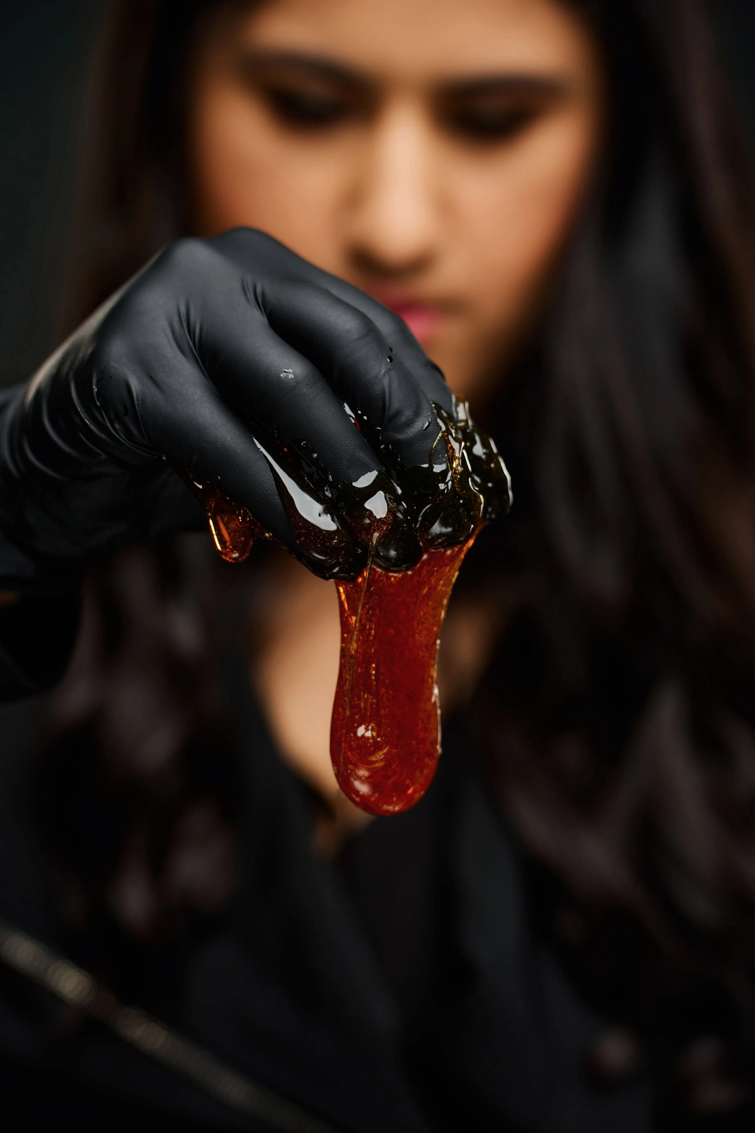 Woman holding sugaring wax with her hand as it drips