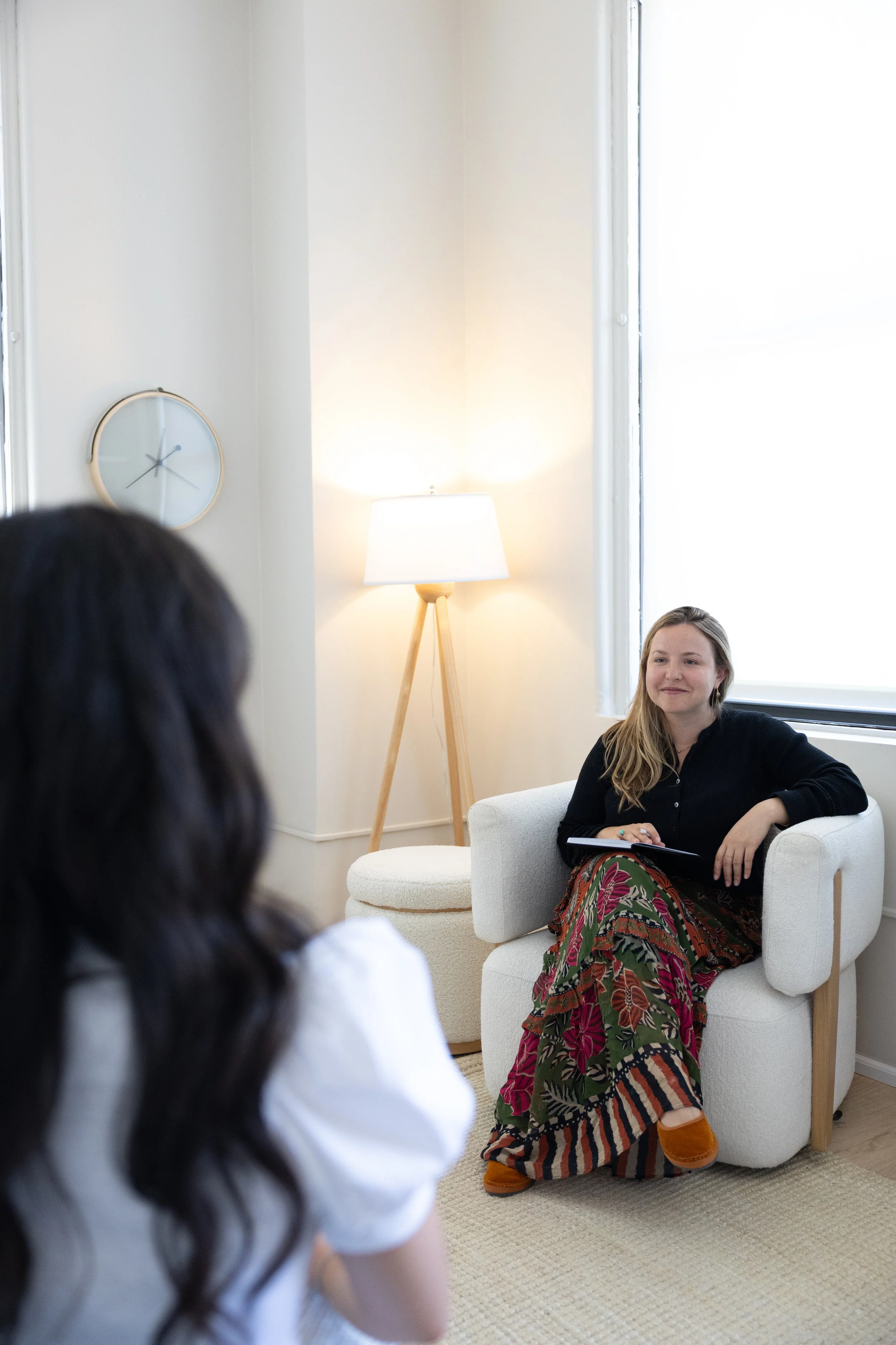 Meghan Lacy, a couples therapist at Lindsey Turner Therapy providing therapy to a girl with brown hair and a clock on the wall
