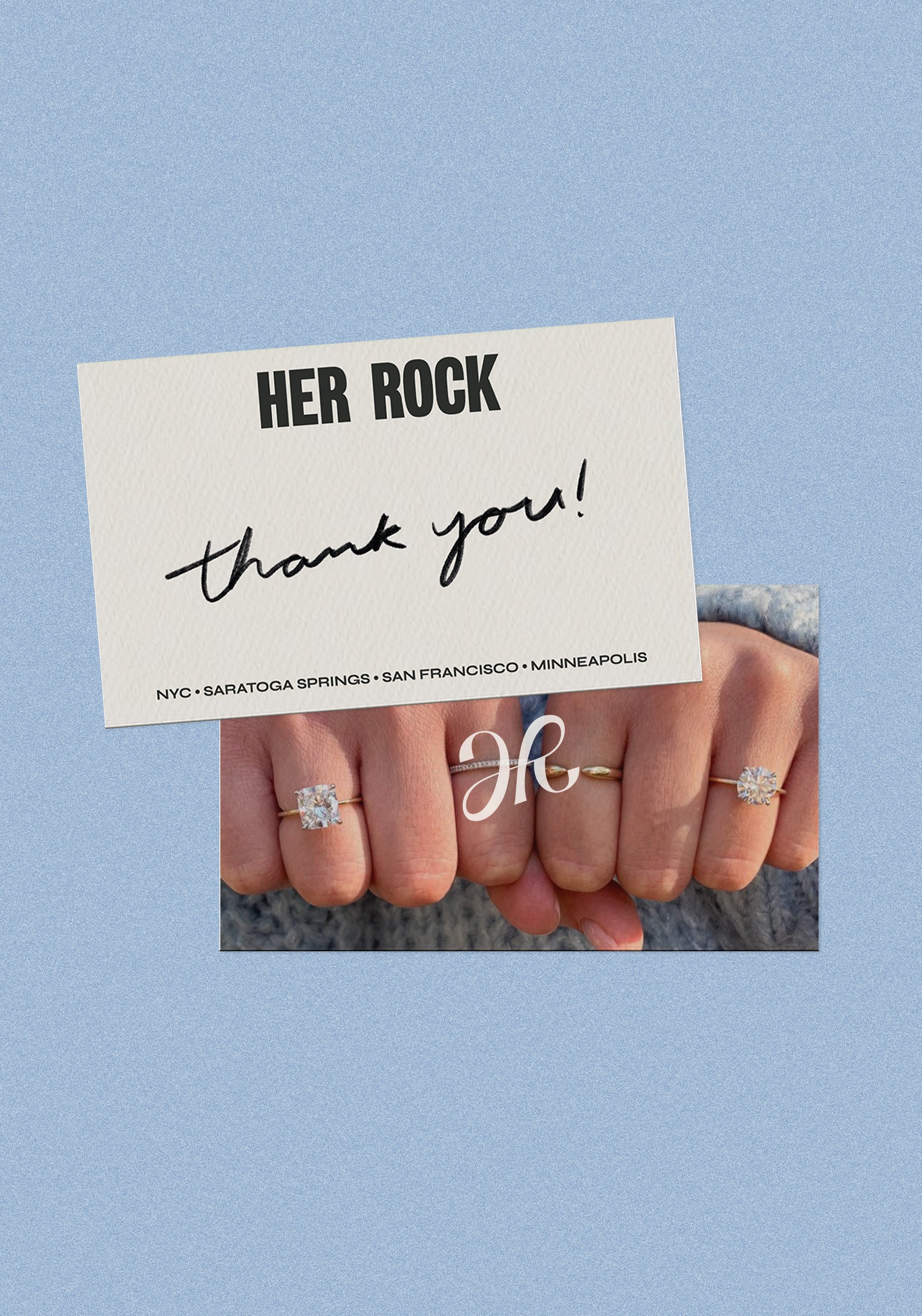 Close-up of a person's hand showing multiple rings, holding a white card that says "HER ROCK" and "thank you!" with city names at the bottom, against a blue sky background.
