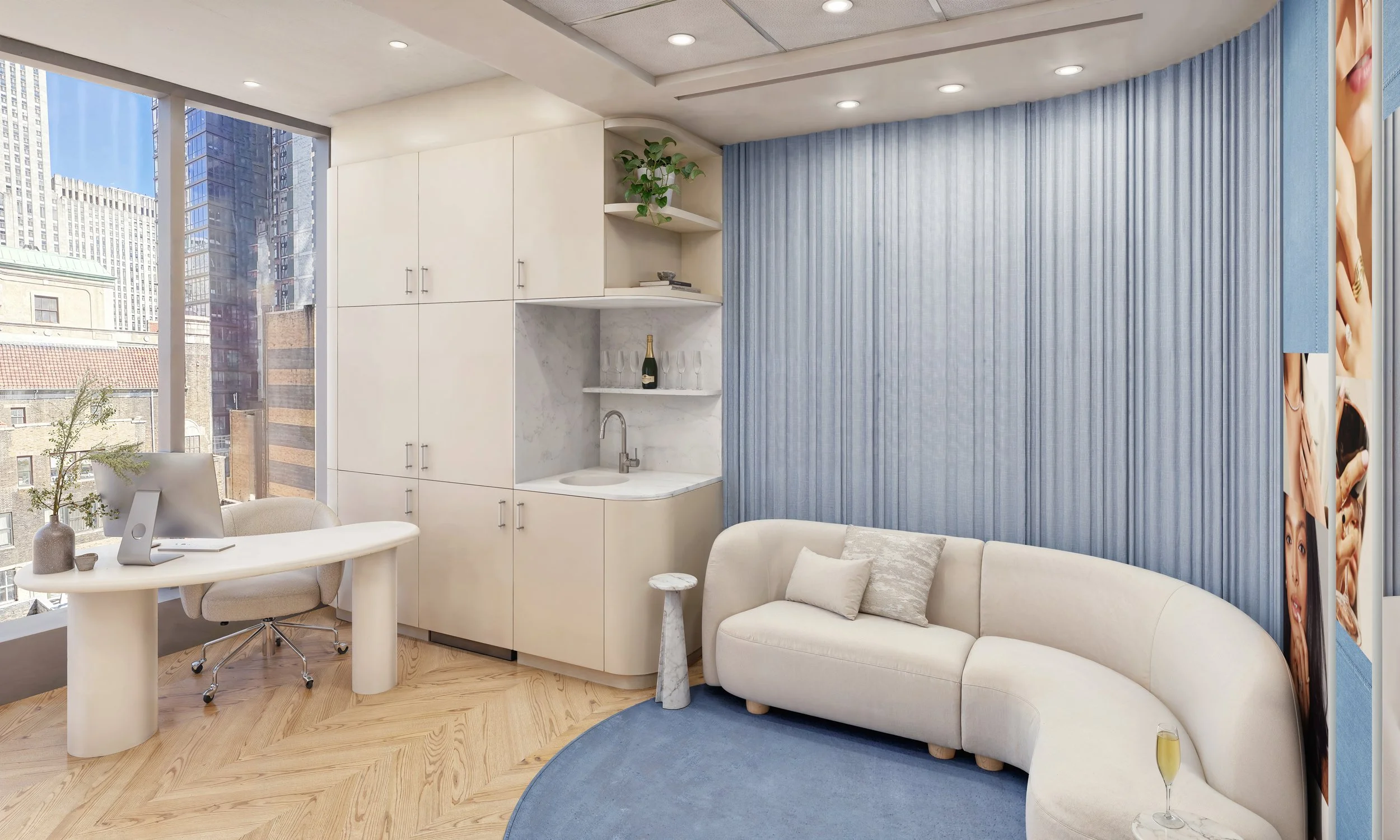 Modern office with white curved sofa, small round marble side table, and desk with computer near large windows showing city buildings, blue curtains on wall, built-in cabinets, and decorative items including wine and glassware.