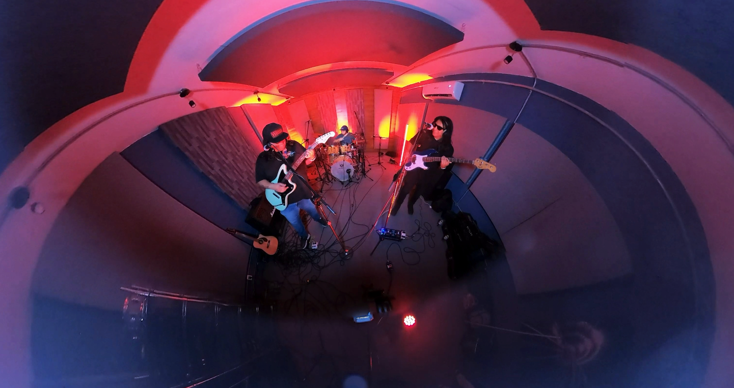 A band performing in a recording studio with colorful red and yellow lighting.