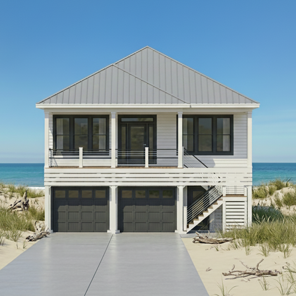 Two-story beach house with a gray metal roof, white siding, black window frames, and a two-car garage, situated on sandy dunes with beach grass, overlooking the ocean under a clear blue sky.