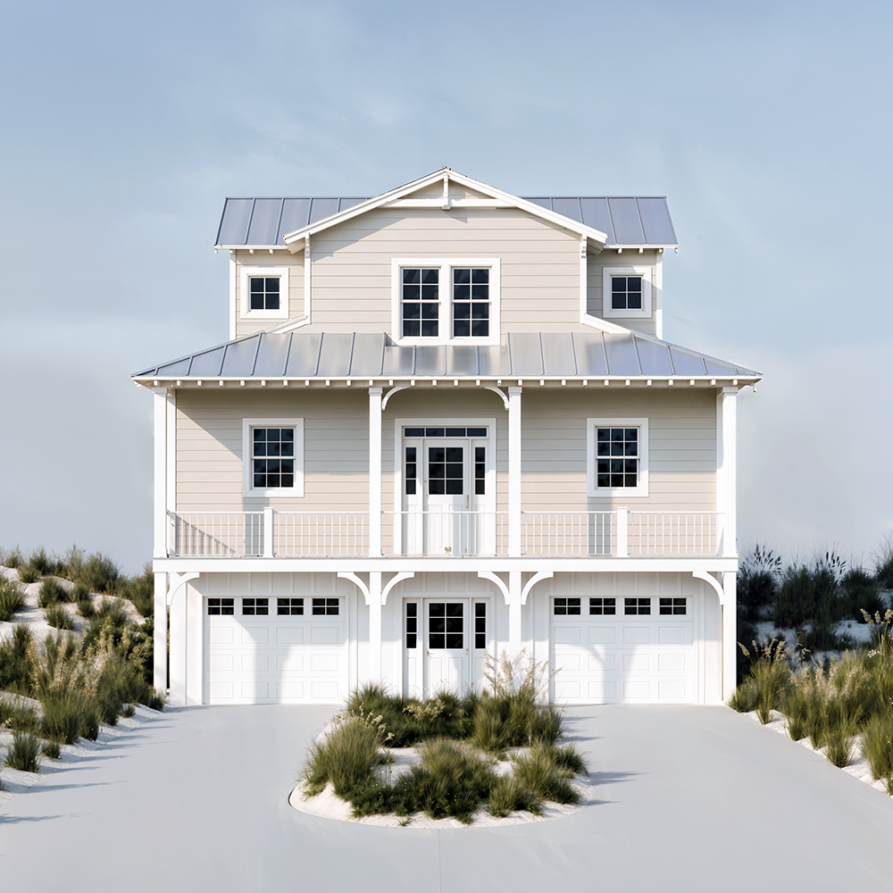 A modern multi-story beach house with a light-colored exterior, metal roofing, and a garage. It has a front porch and is surrounded by sand and beach vegetation.
