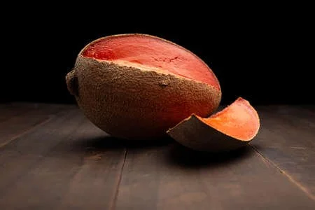 180553969-still-life-image-of-one-mexican-red-mamey-close-up-on-rustic-wooden-surface-and-black-background.jpg