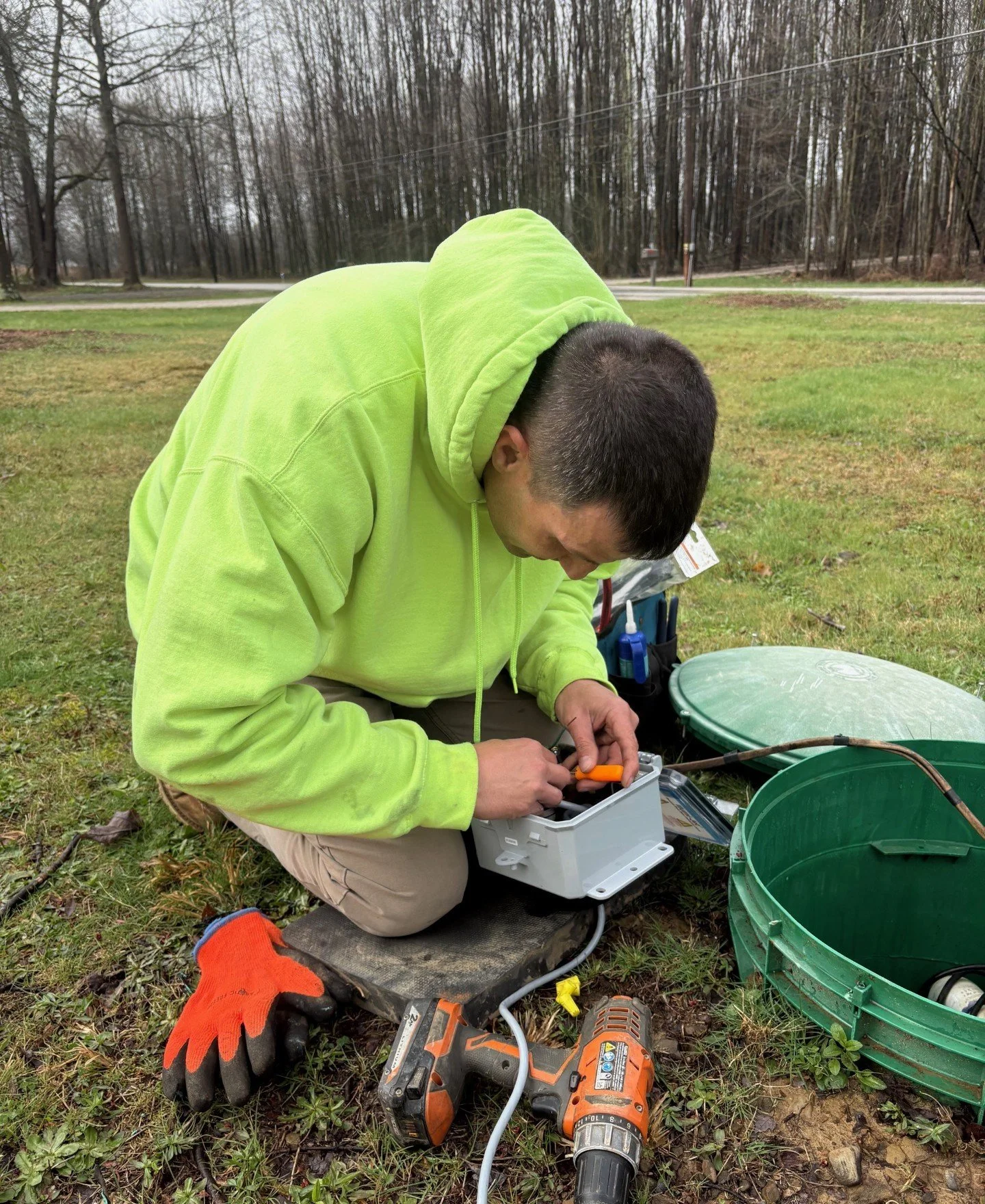 Aeration Septic Inc service professional working on control panel next to septic system