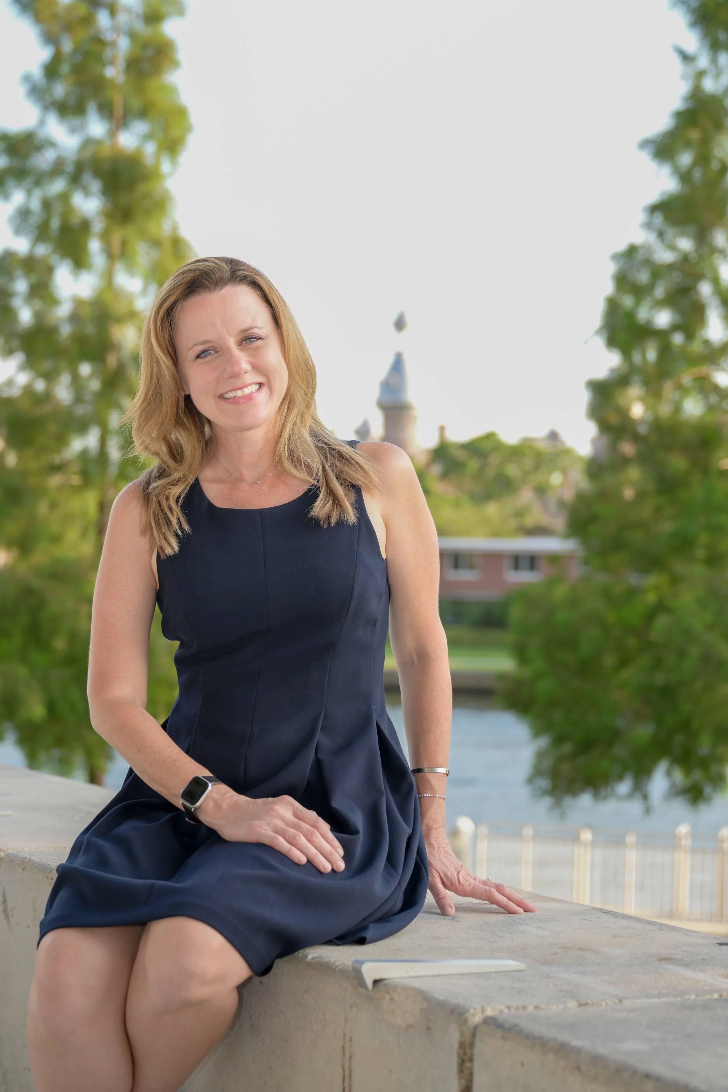 A photograph showing Dr. Rebekah Hellier seated on a stone wall in Downtown Tampa, Florida smiling.