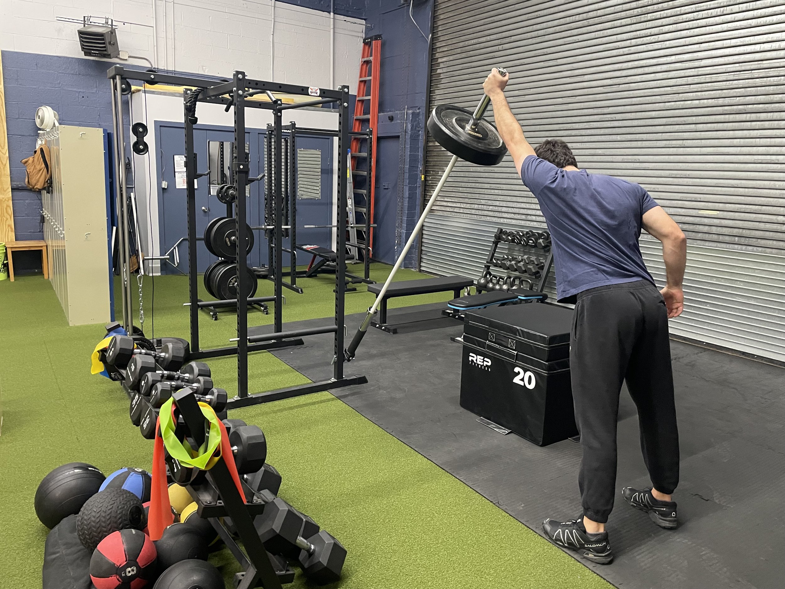 Man lifting a barbell with weight plates attached in a gym.