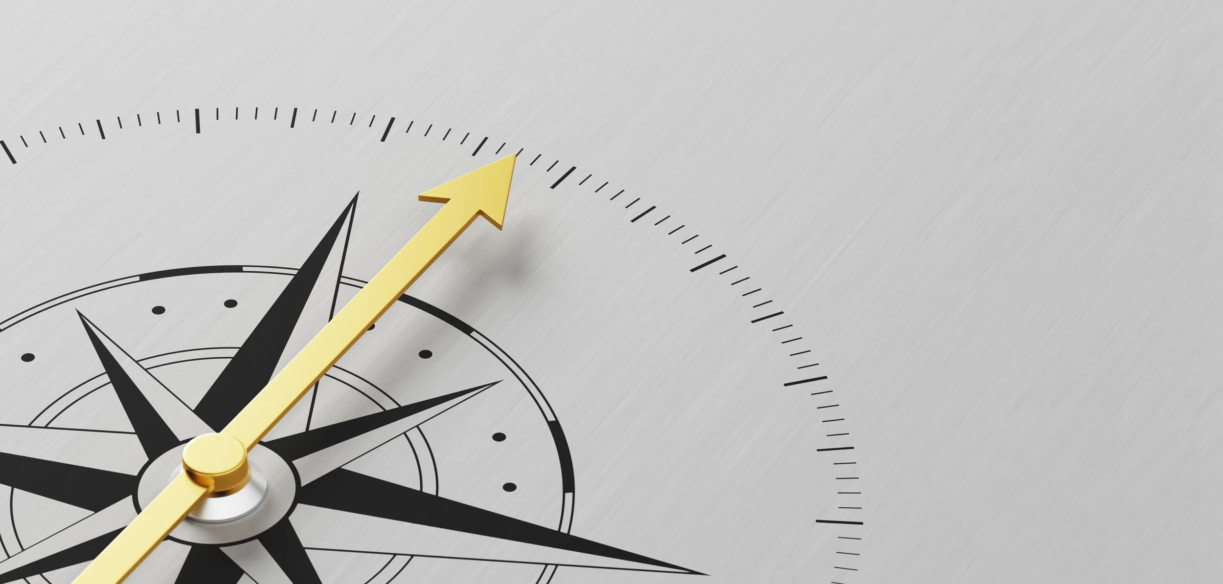 Close-up of a compass with a yellow arrow pointing northeast on a metallic surface.