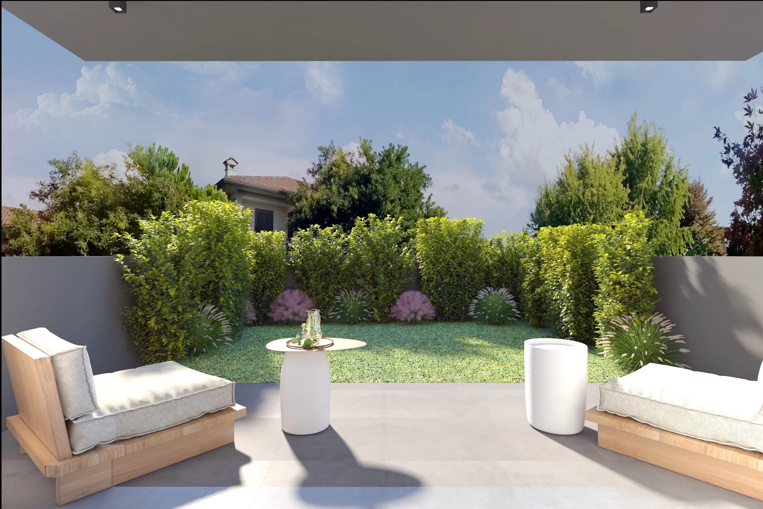 Modern outdoor patio with cushioned lounge chairs, a small round table with a glass pitcher and glasses, overlooking a well-maintained backyard with green bushes and trees under a partly cloudy sky.