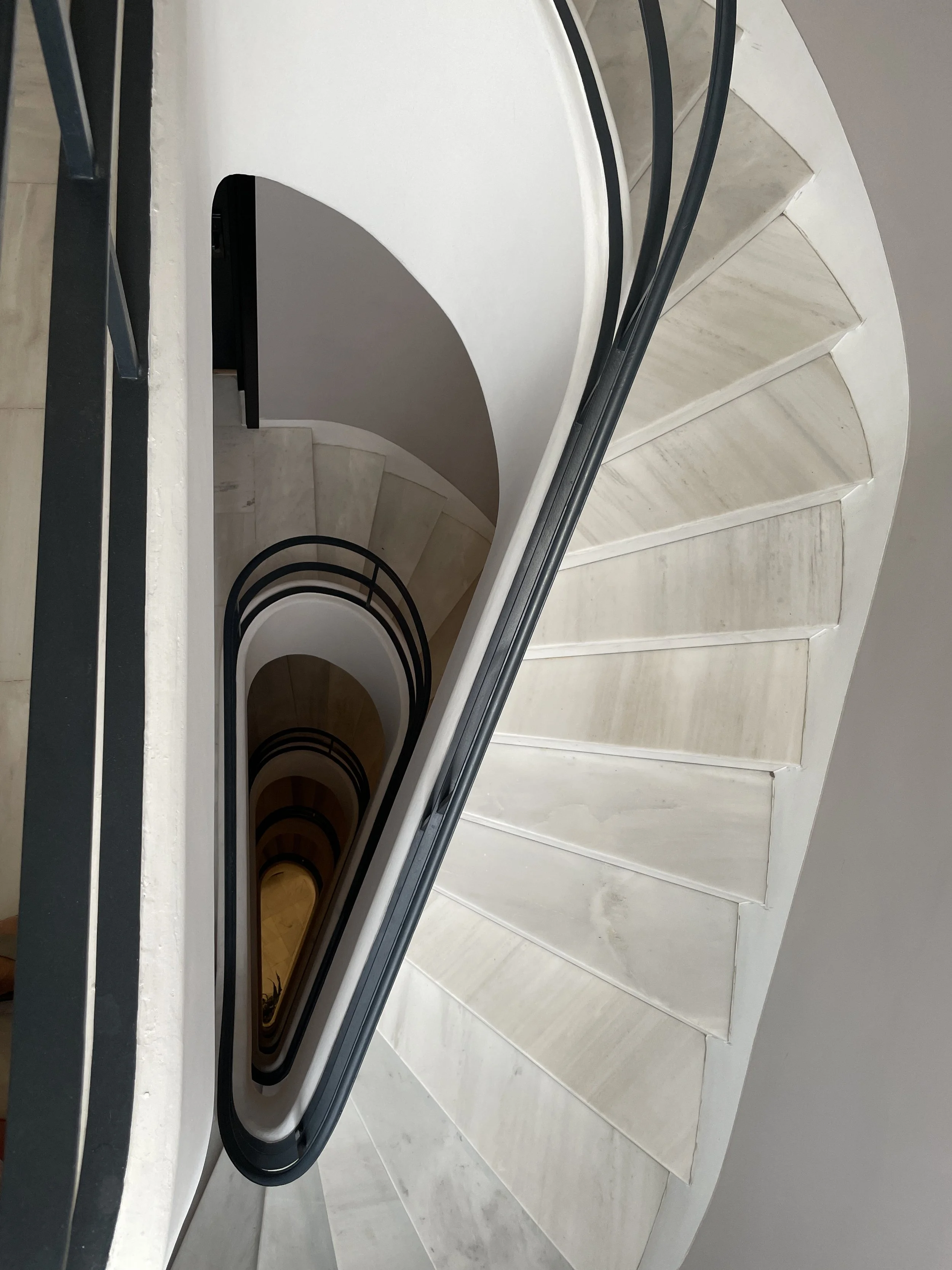 Spiral staircase viewed from above, showing the white steps and black railing.