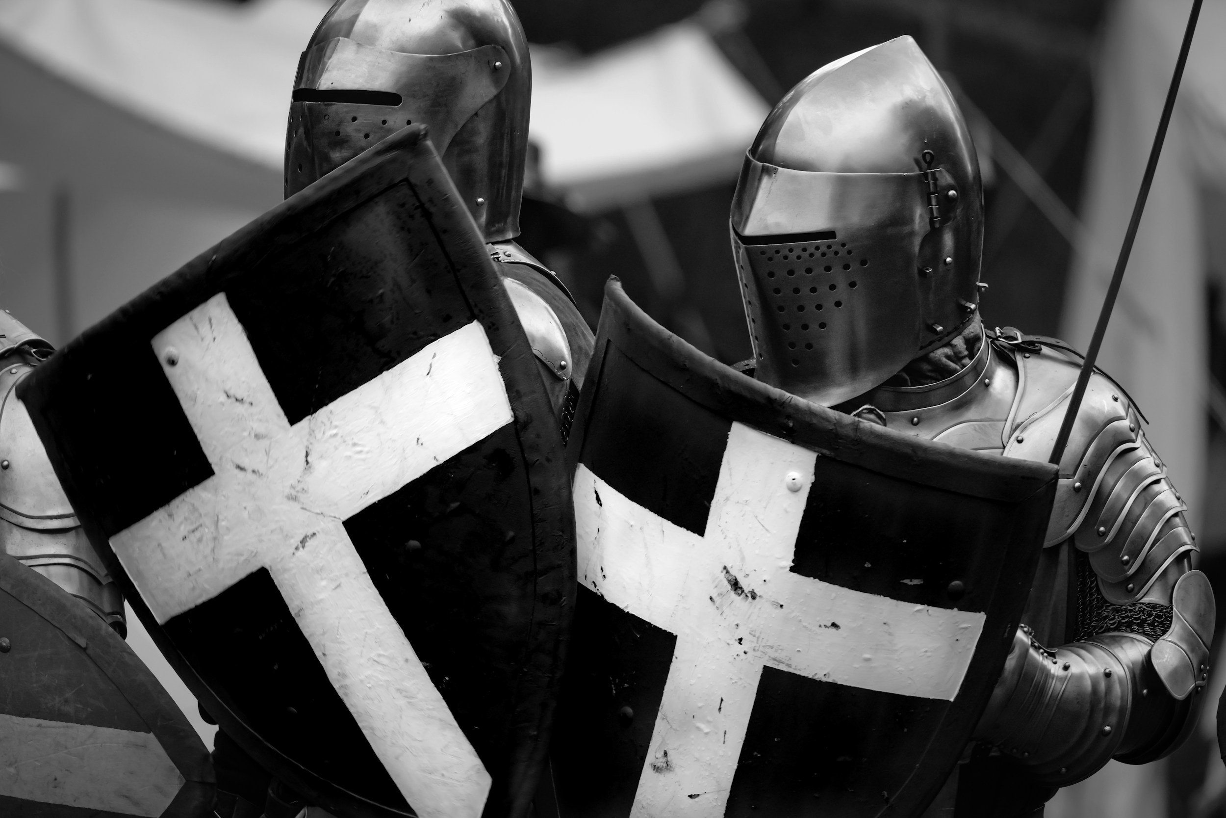 Two medieval knights in armor holding shields with white crosses, engaged in a duel or combat.