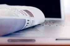 Close-up of a newspaper open on a laptop keyboard