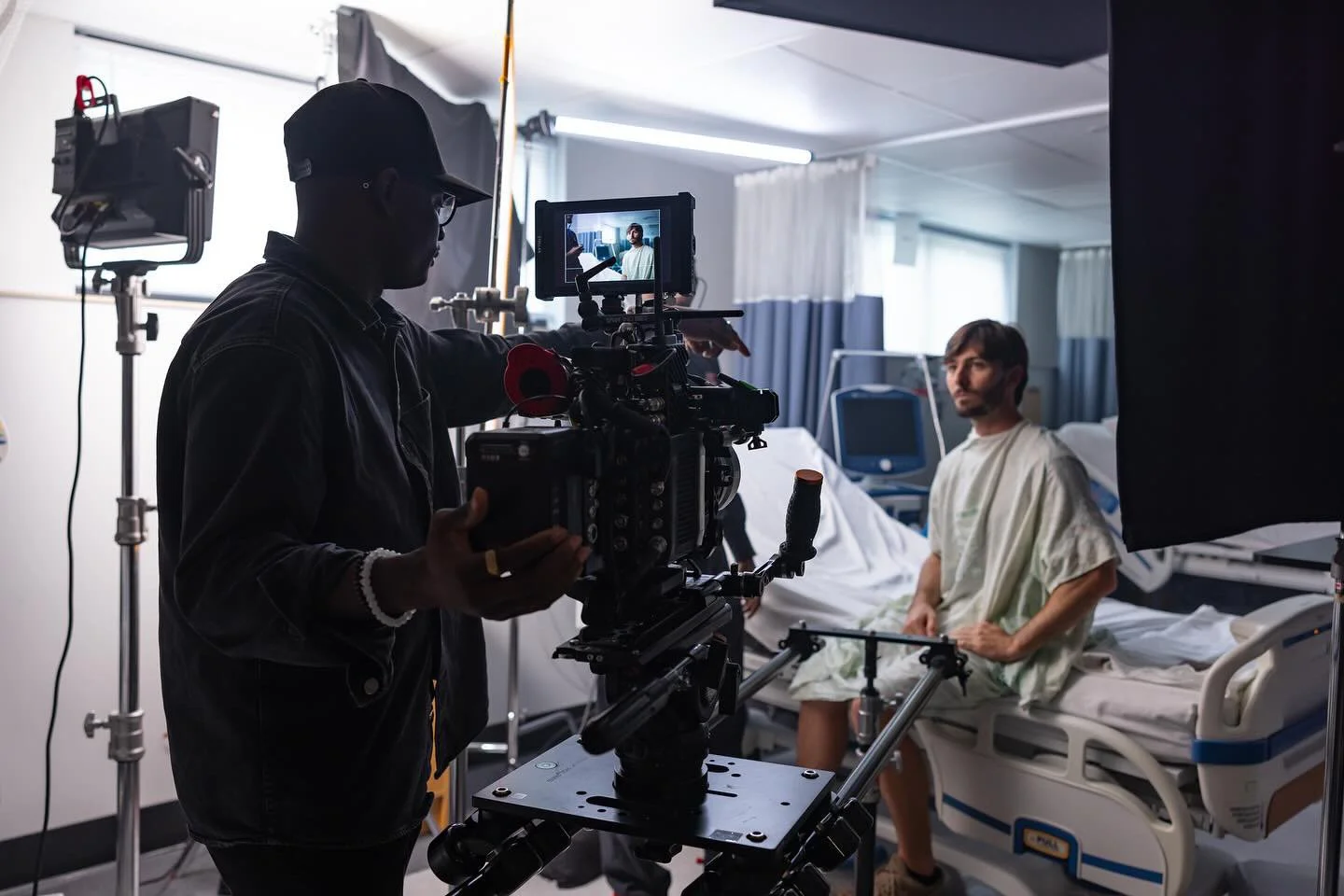Filmmaker operating camera on hospital set with actor in hospital bed