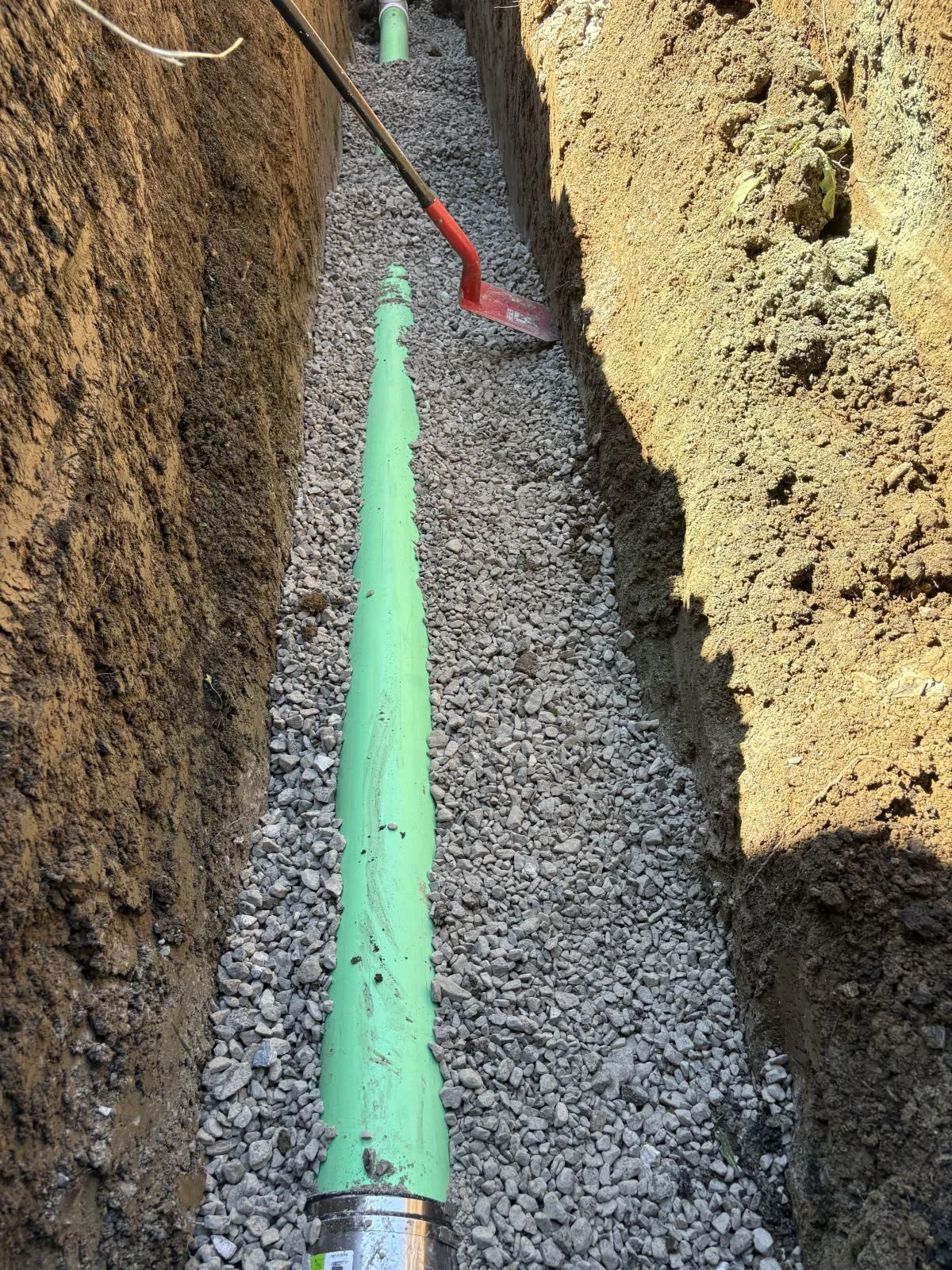 Sewer pipe set in gravel bedding in an open trench