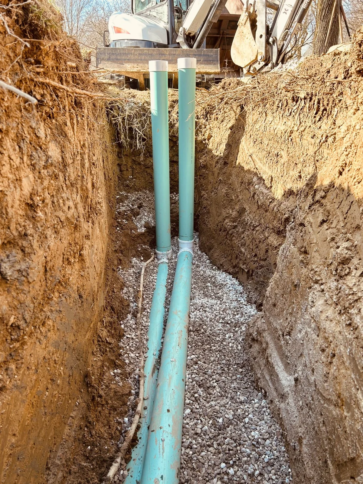 New sewer lines installed in an open trench with an excavator on site