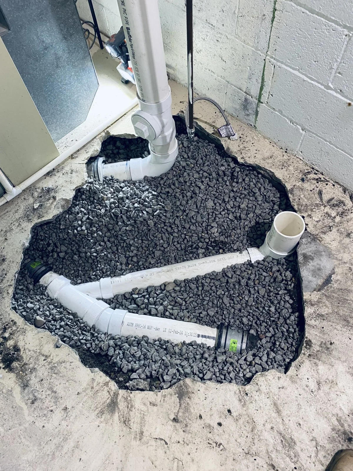 New PVC drain lines with wye fittings and cleanouts under a basement floor, set in gravel