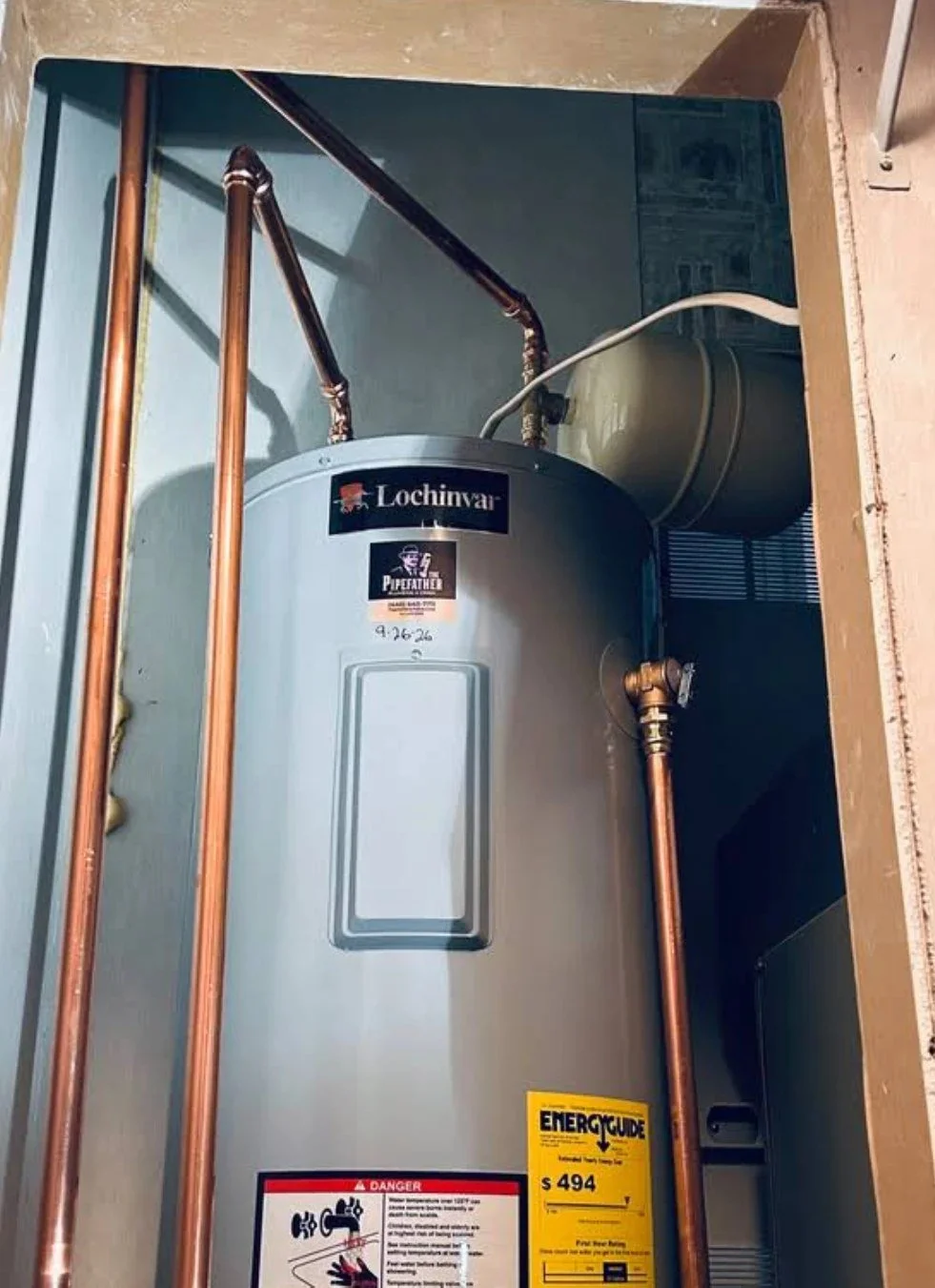 New electric tank water heater with copper piping and a wall-mounted expansion tank