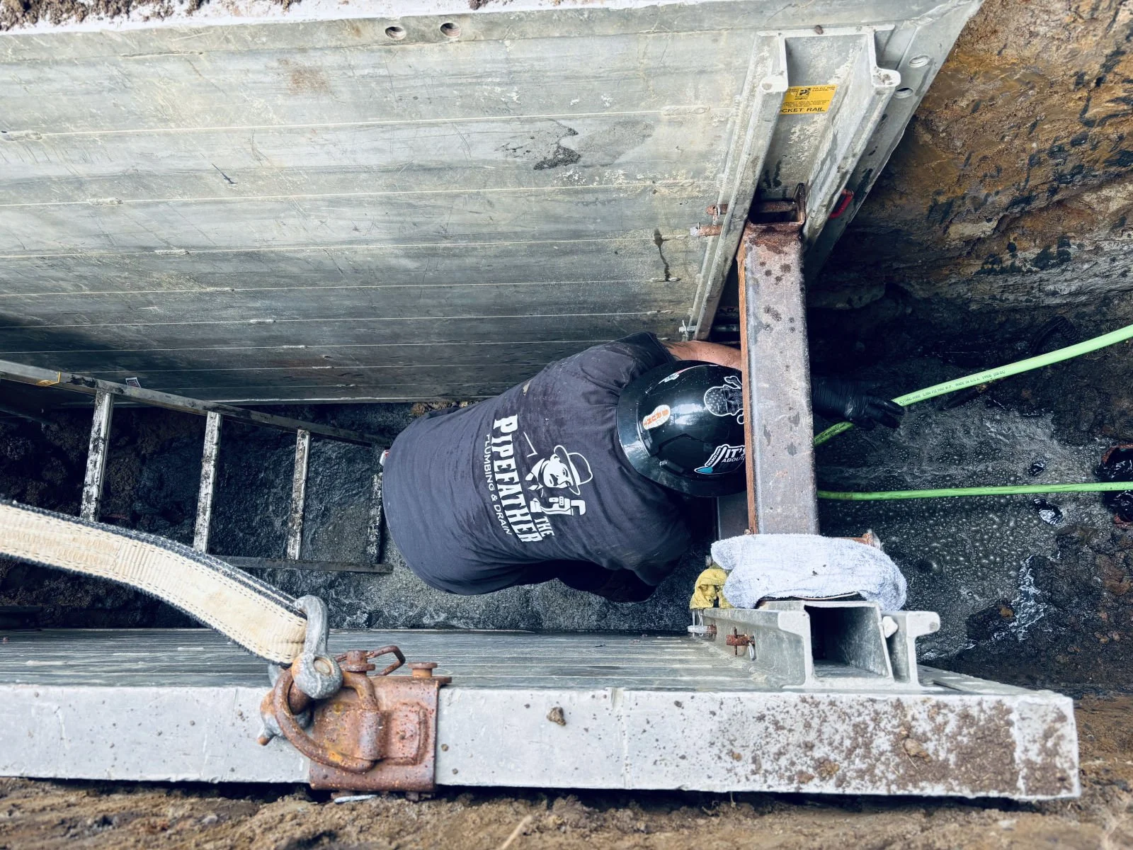 Pipefather plumber hydro jetting a sewer line from inside a shored trench