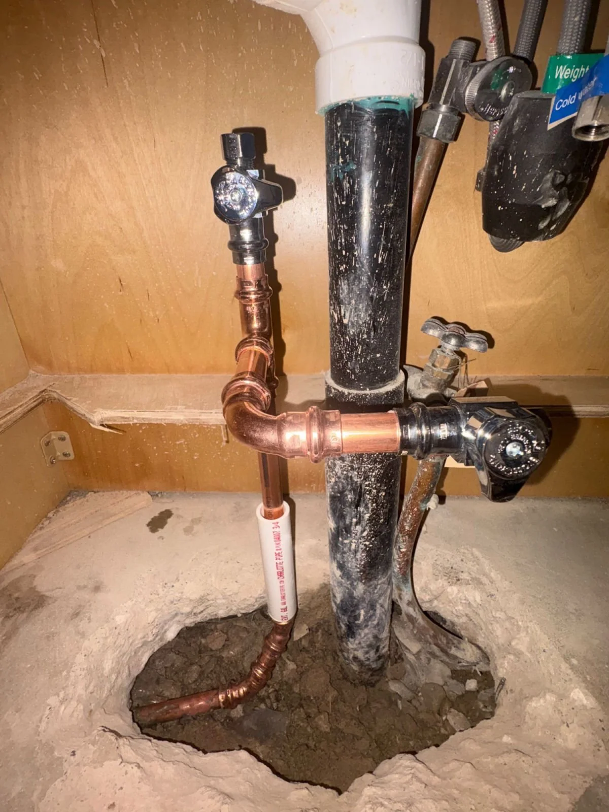 New copper water line with shutoff valves coming up through the slab under a sink