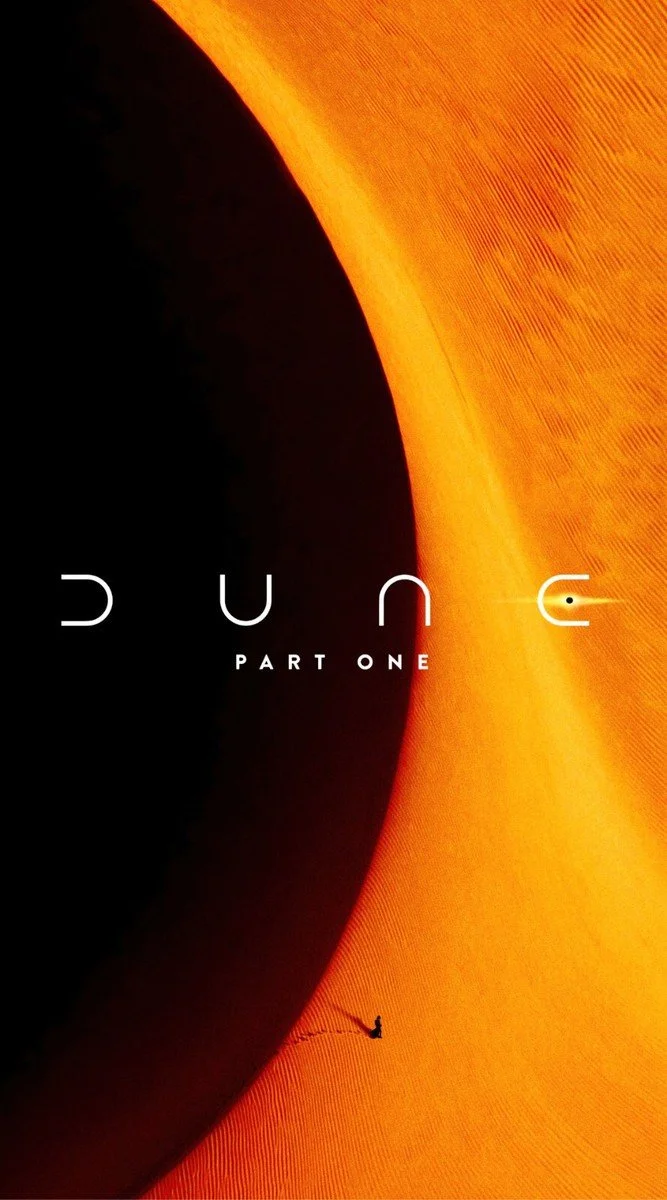 A person riding a camel on a vast, orange desert with a large, dark shadow or rock formation on the left side of the image, featuring the text 'Dune Part One' in the center.