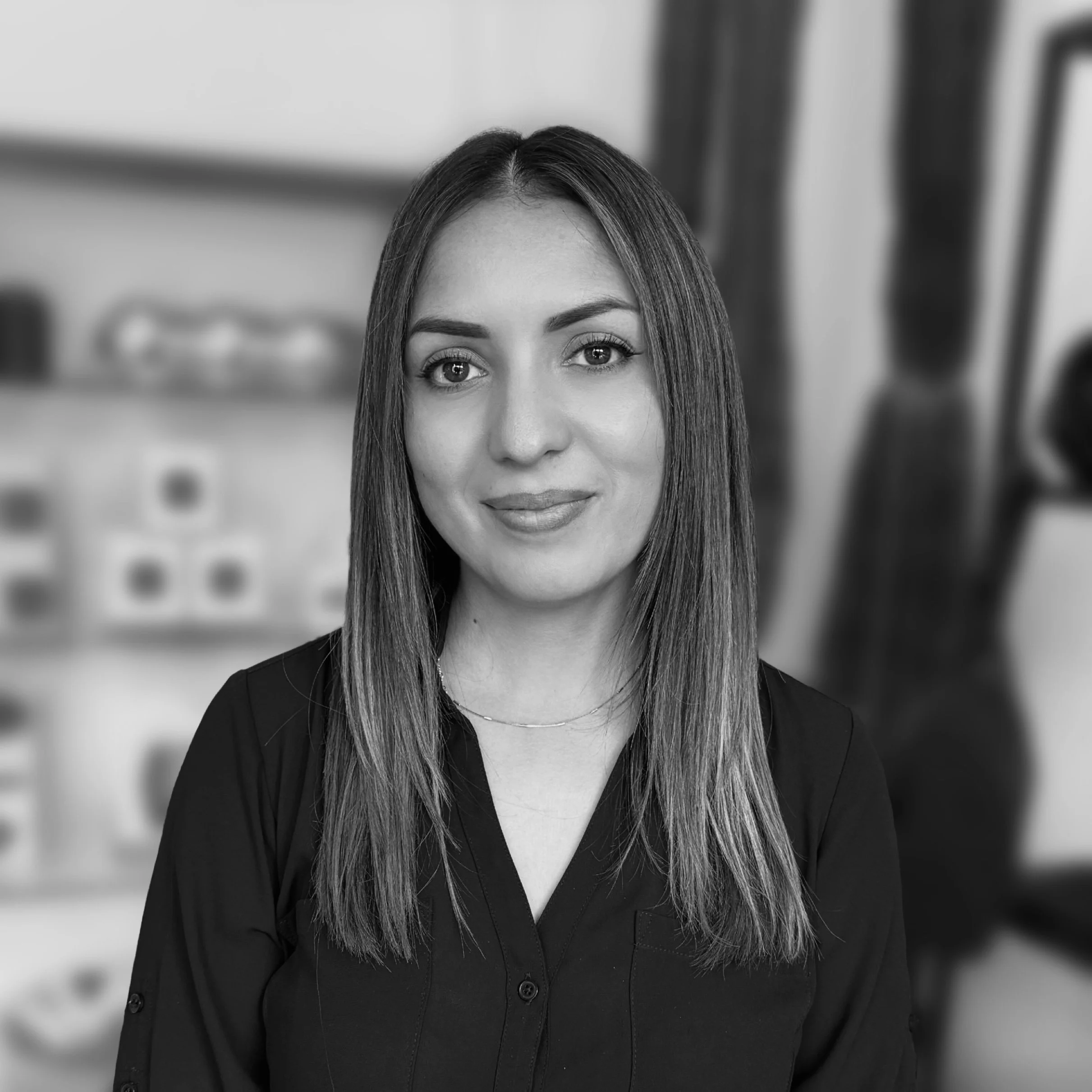 Black and white portrait of a woman with wavy, shoulder-length hair, smiling slightly, wearing a dark shirt, against a plain background.