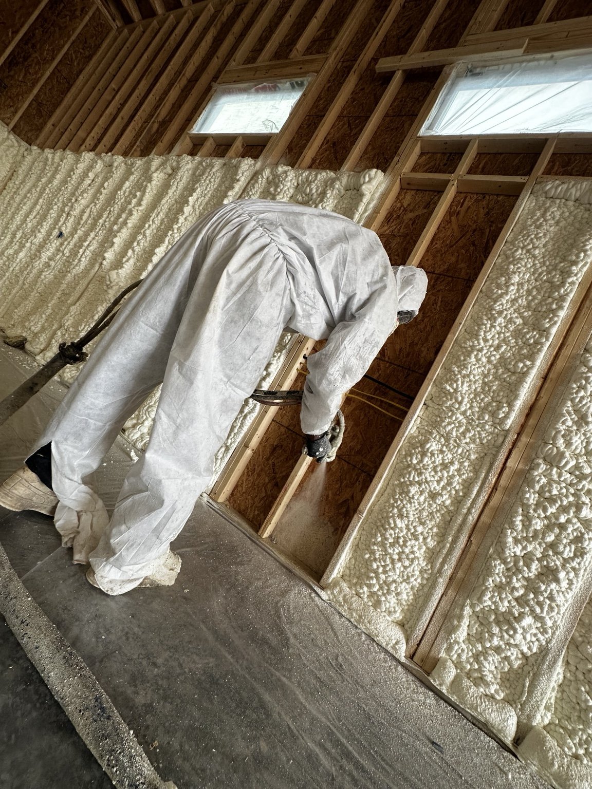 Reliable Insulation installer applying spray foam inside a framed Texas building.