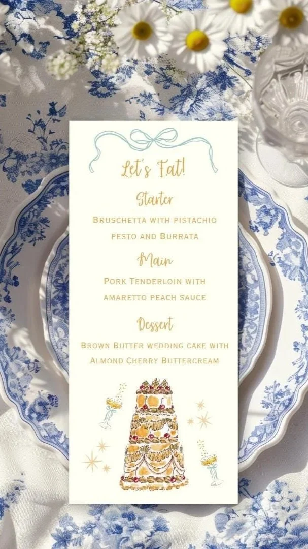 Wedding menu card with a cake illustration, placed on a blue and white floral tablecloth with daisy flowers in the background.