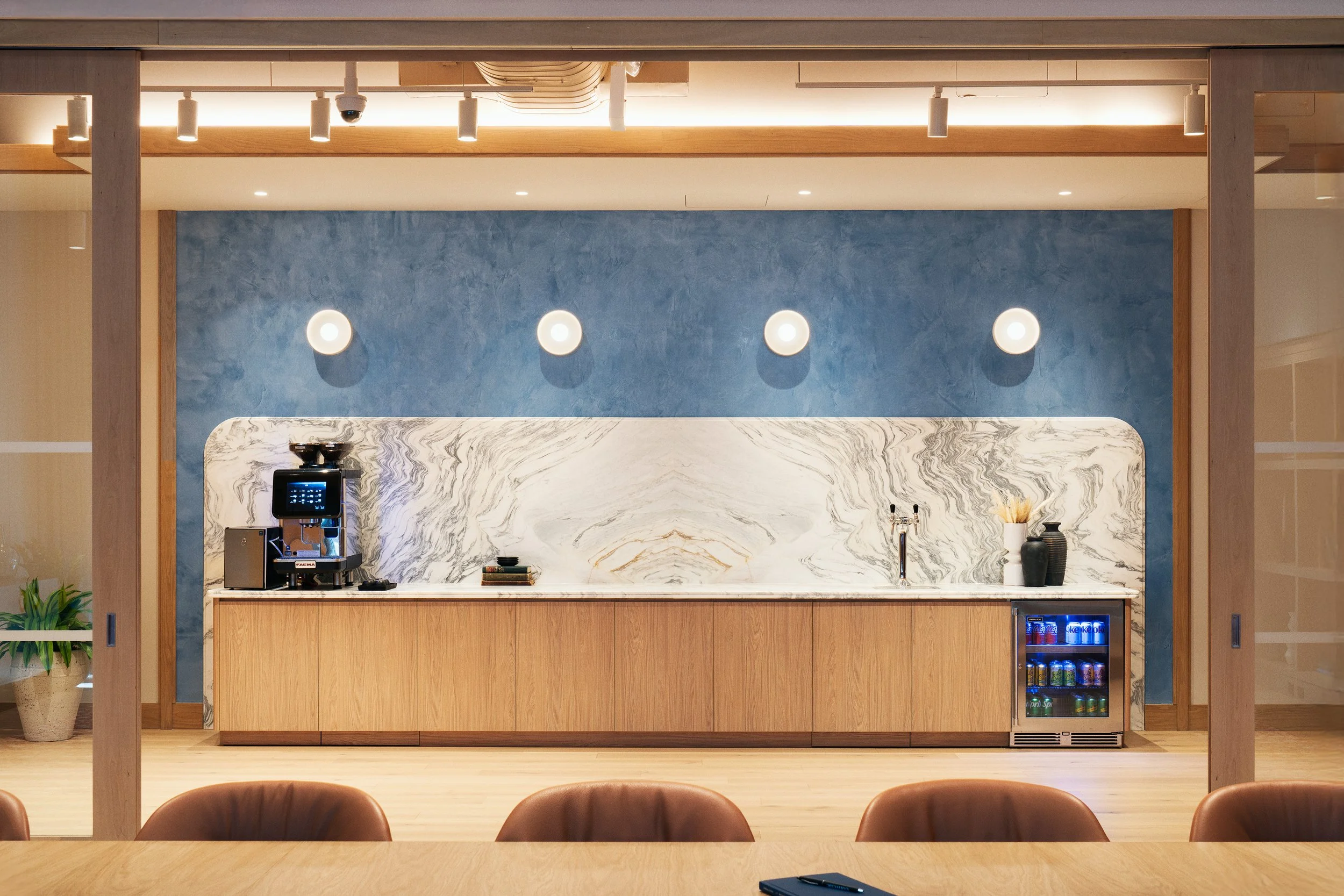 Boardroom's built-in oak millwork counter with a marble backsplash, blue plaster wall, and round wall sconces, Scholastic Building SoHo NYC
