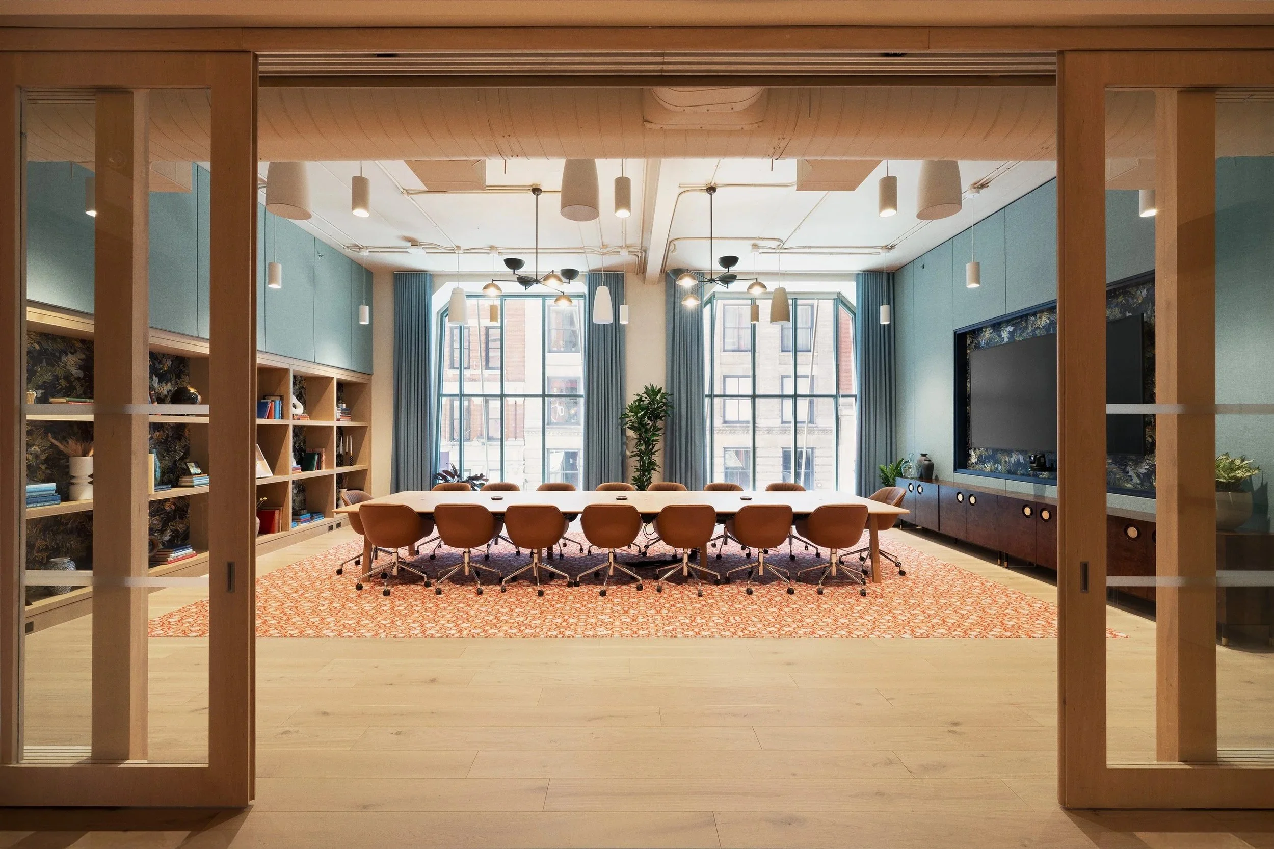 Boardroom featuring floor-to-ceiling arched windows, built-in oak shelving, and upholstered wall paneling, Scholastic Building SoHo NYC