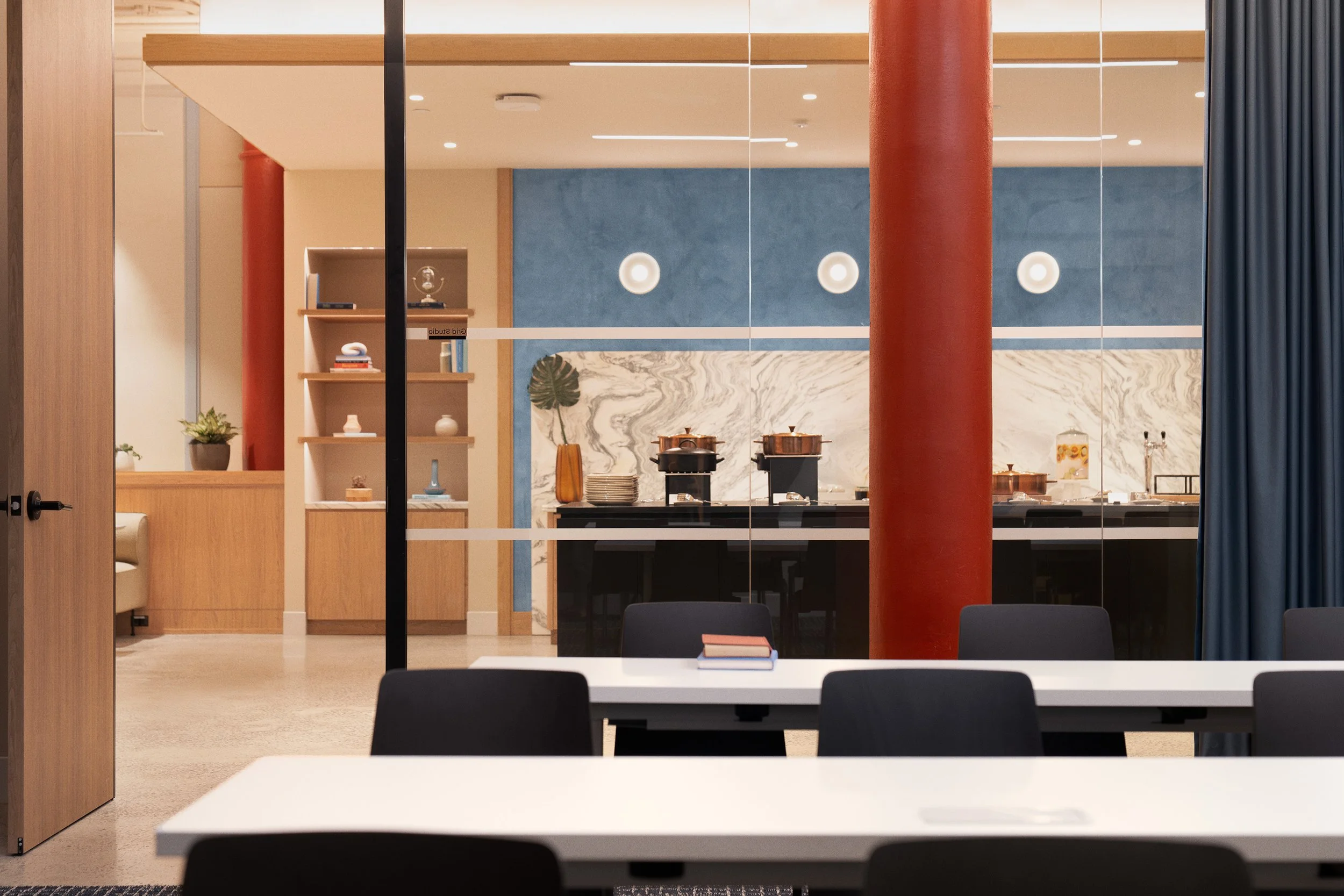 Studio featuring a marble backsplash, built-in oak shelving, and a red cast-iron column against a blue accent wall, Scholastic Building SoHo NYC