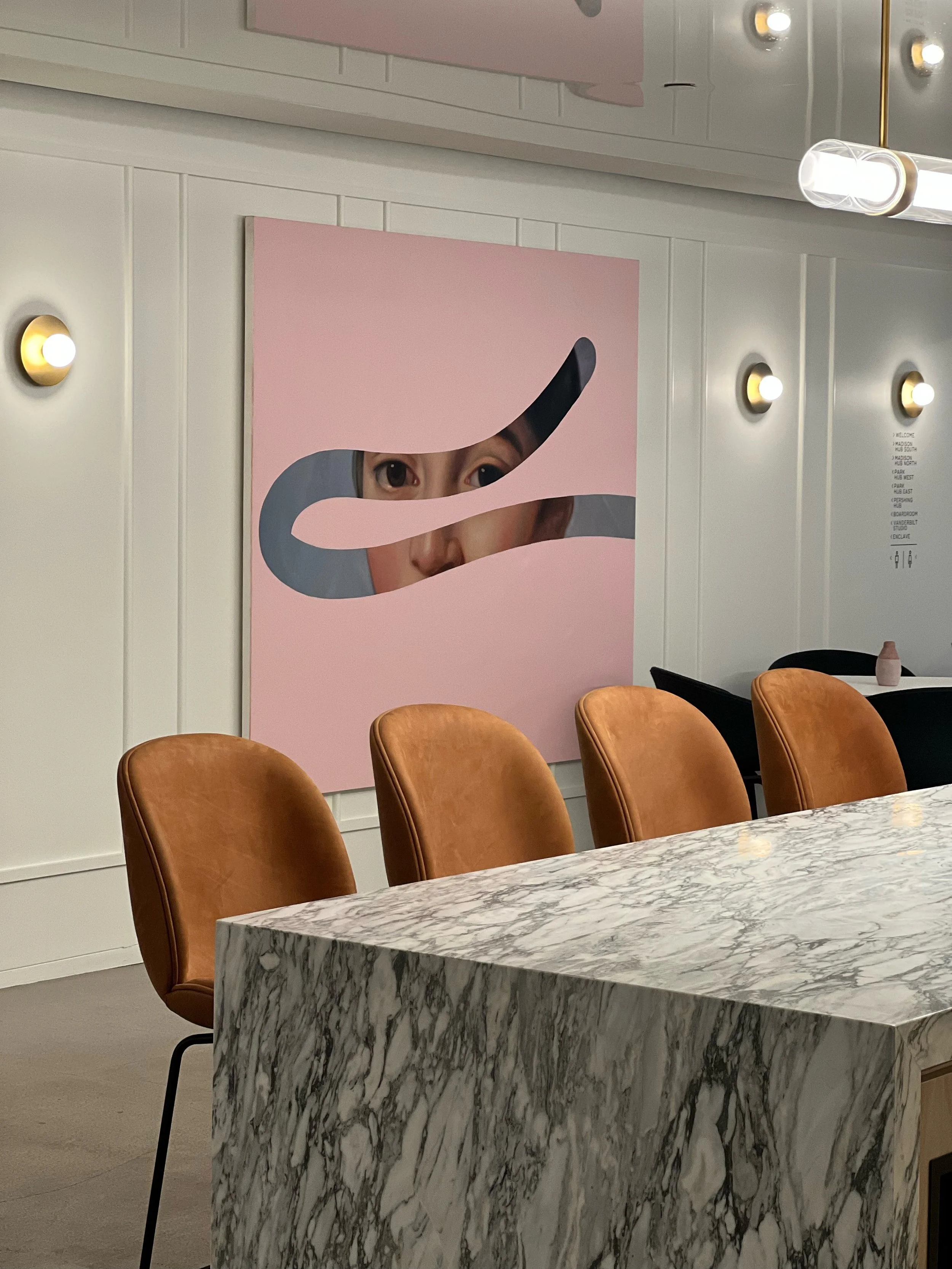 Large custom island with marble countertops and cognac leather chairs beneath a pink abstract portrait artwork at Convene Hospitality Group, 101 Park Avenue, NYC