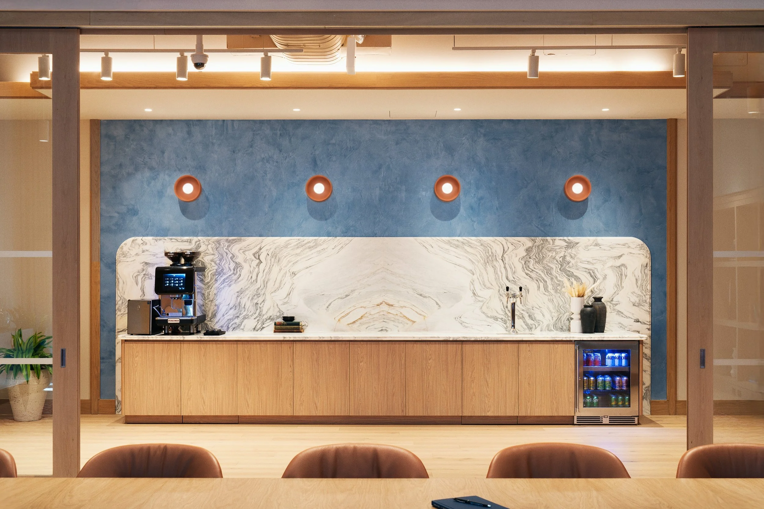Boardroom's built-in oak millwork counter with a marble backsplash, blue plaster wall, and round wall sconces, Scholastic Building SoHo NYC