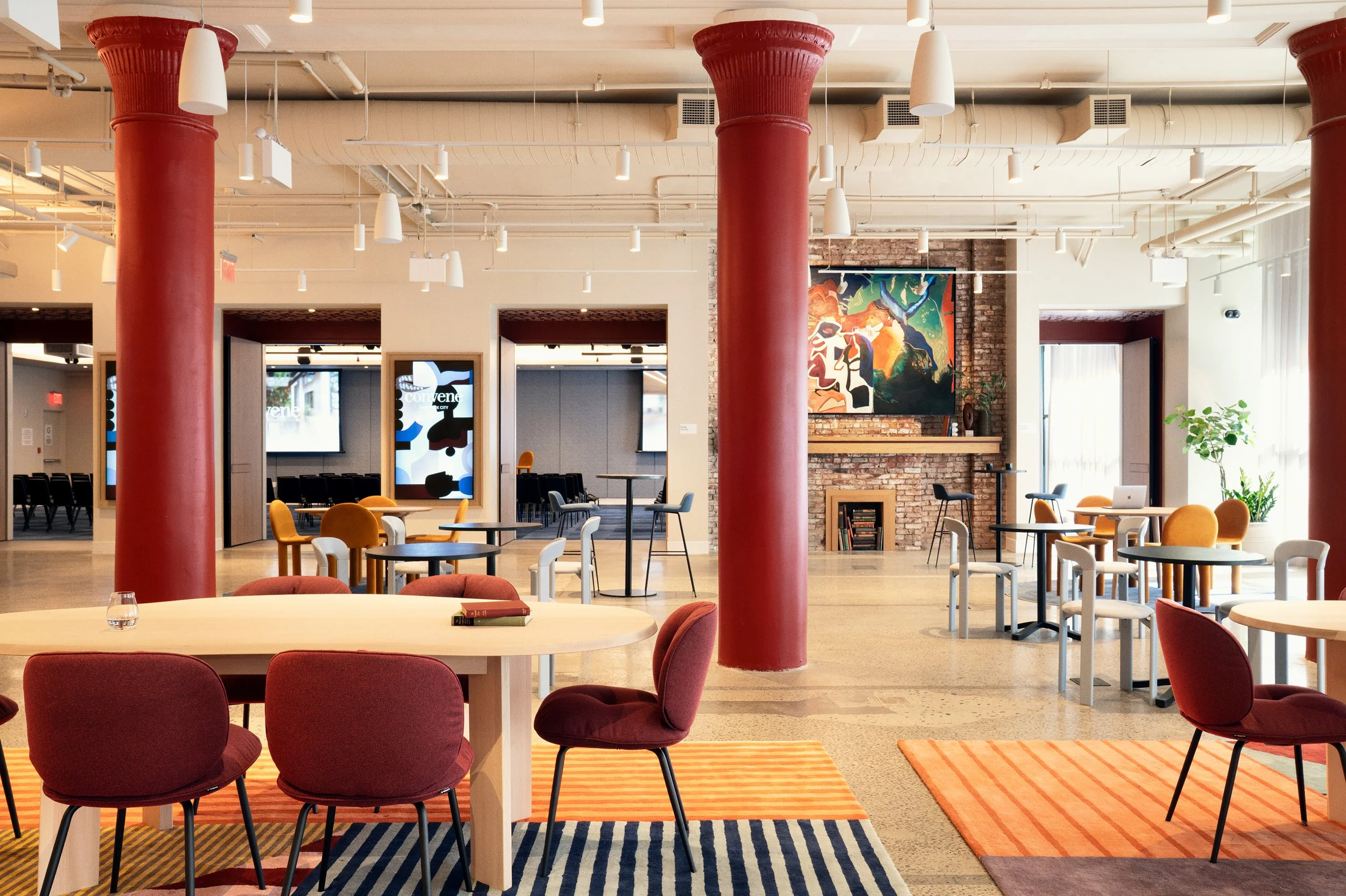 Restored red cast-iron columns and a brick fireplace with framed artwork anchor a mixed lounge seating area in the Scholastic Building, SoHo NYC"