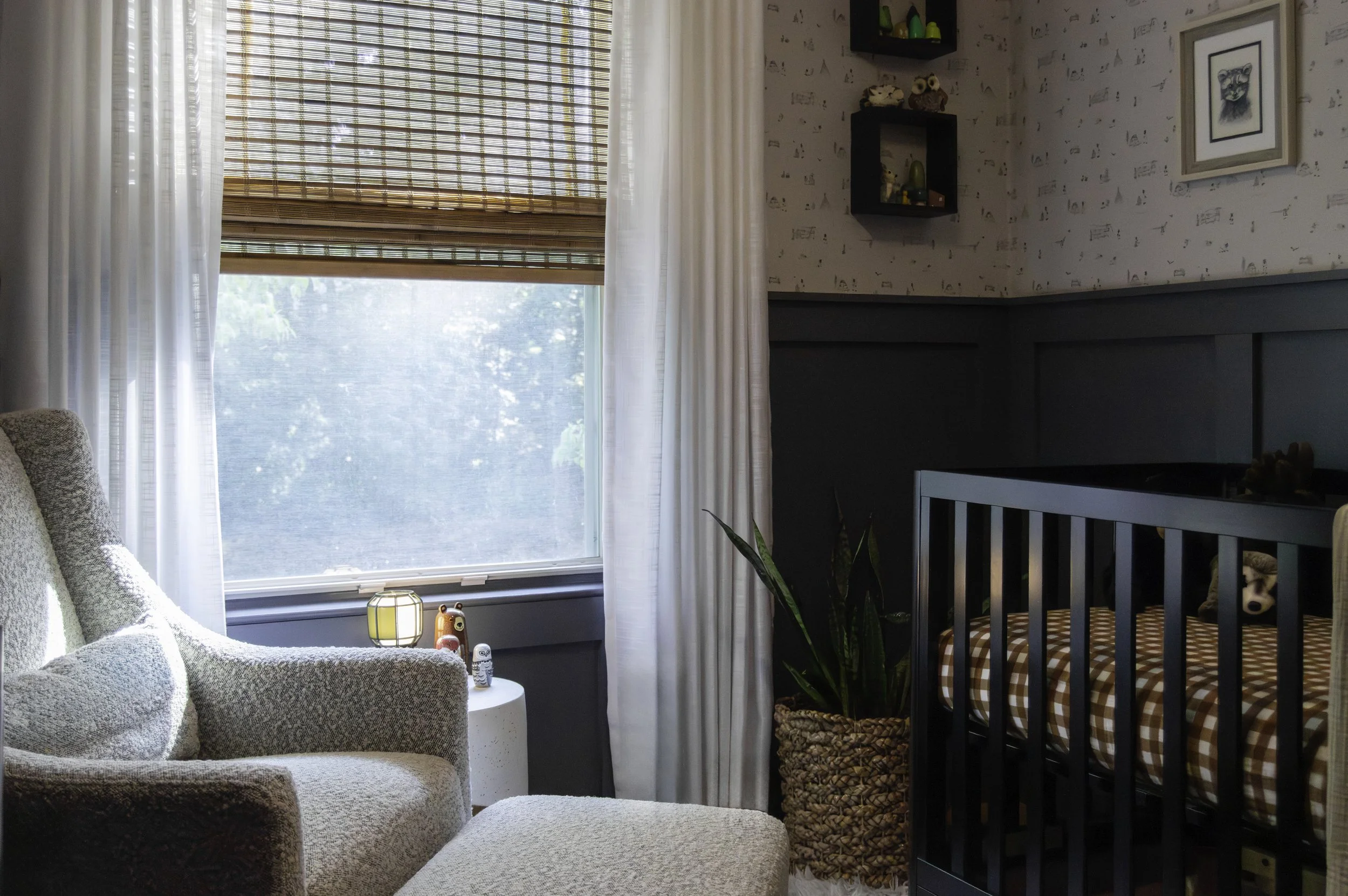 Bouclé glider and ottoman beside a window with woven bamboo shades in a woodland-themed nursery, Reston, VA
