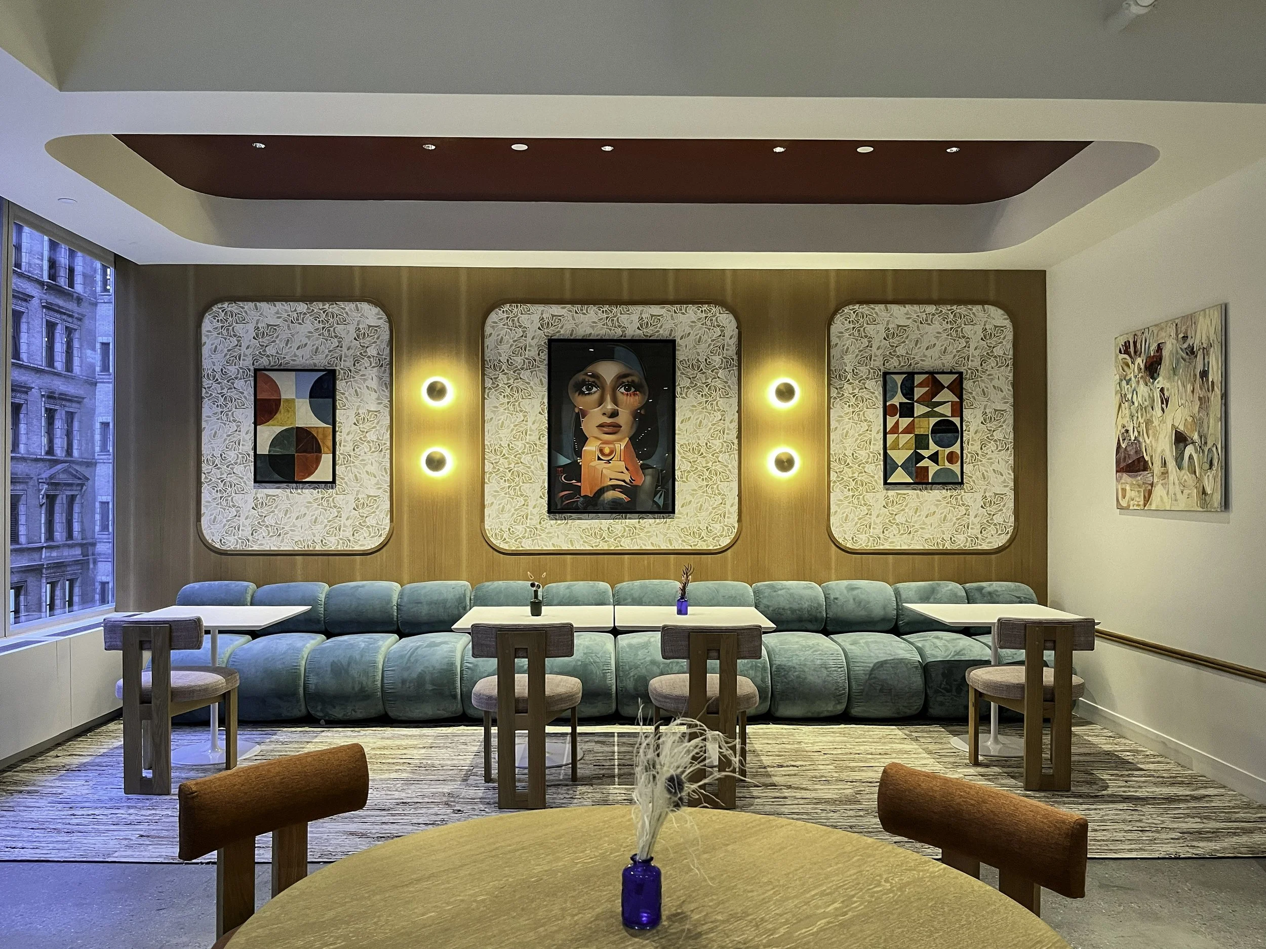 Lounge seating in sage velvet beneath framed pop-art portraits and wall sconces at Convene Hospitality Group, 360 Madison Avenue, NYC