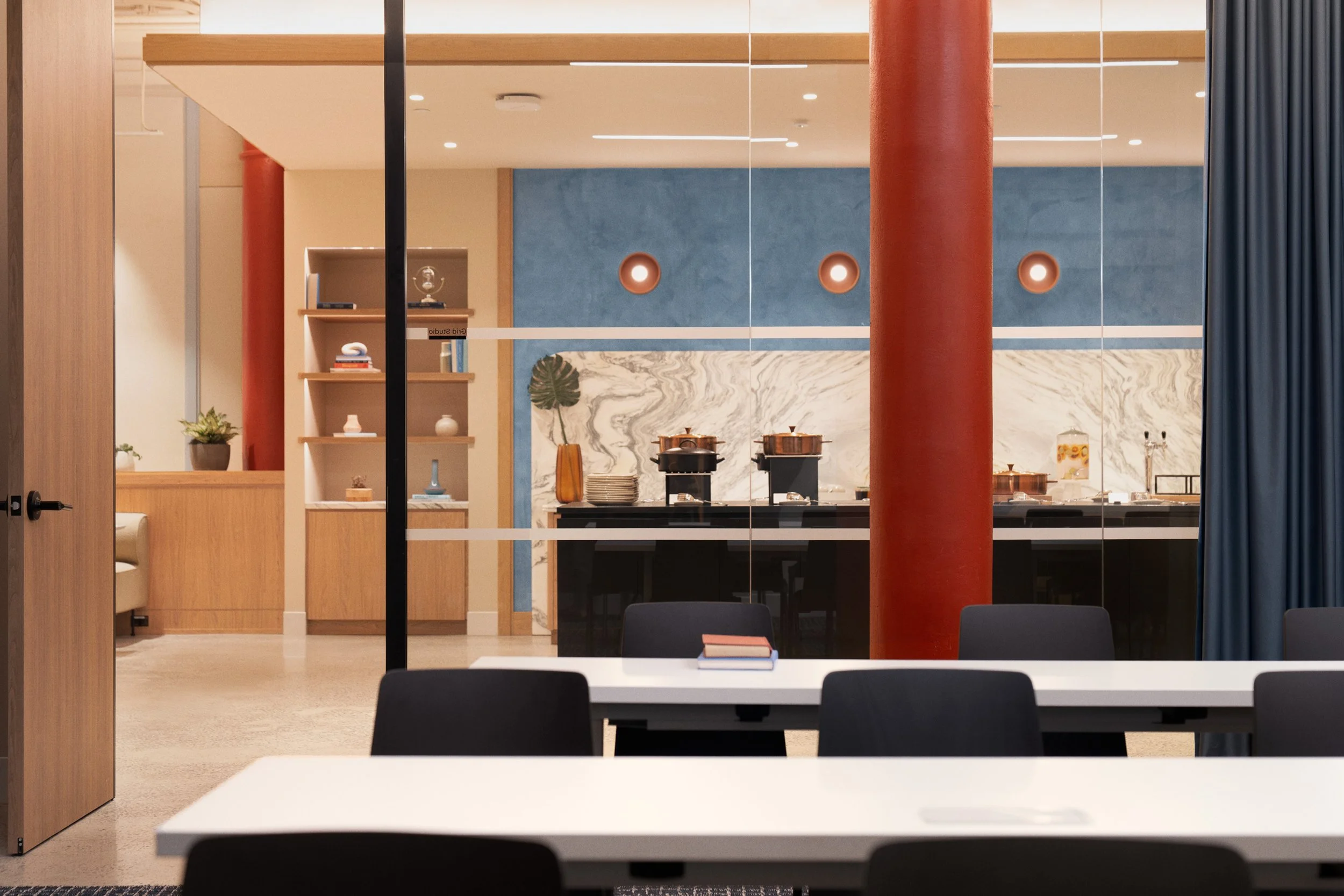 Studio featuring a marble backsplash, built-in oak shelving, and a red cast-iron column against a blue accent wall, Scholastic Building SoHo NYC