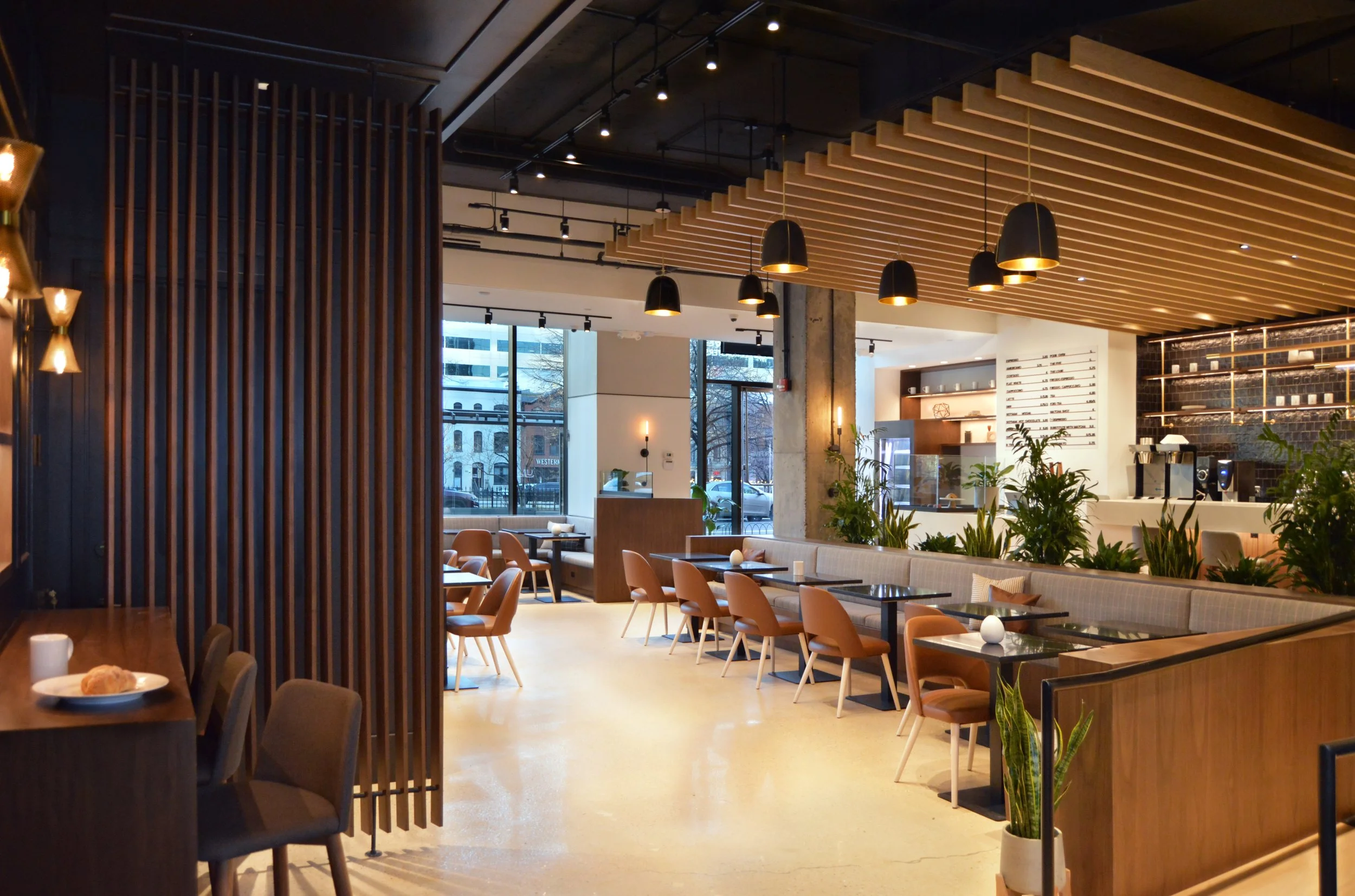 Interior view of For Five Coffee Roasters with wood slat walls, pendant lighting, and a marble-topped bar, part of Marlo and Kroft's portfolio