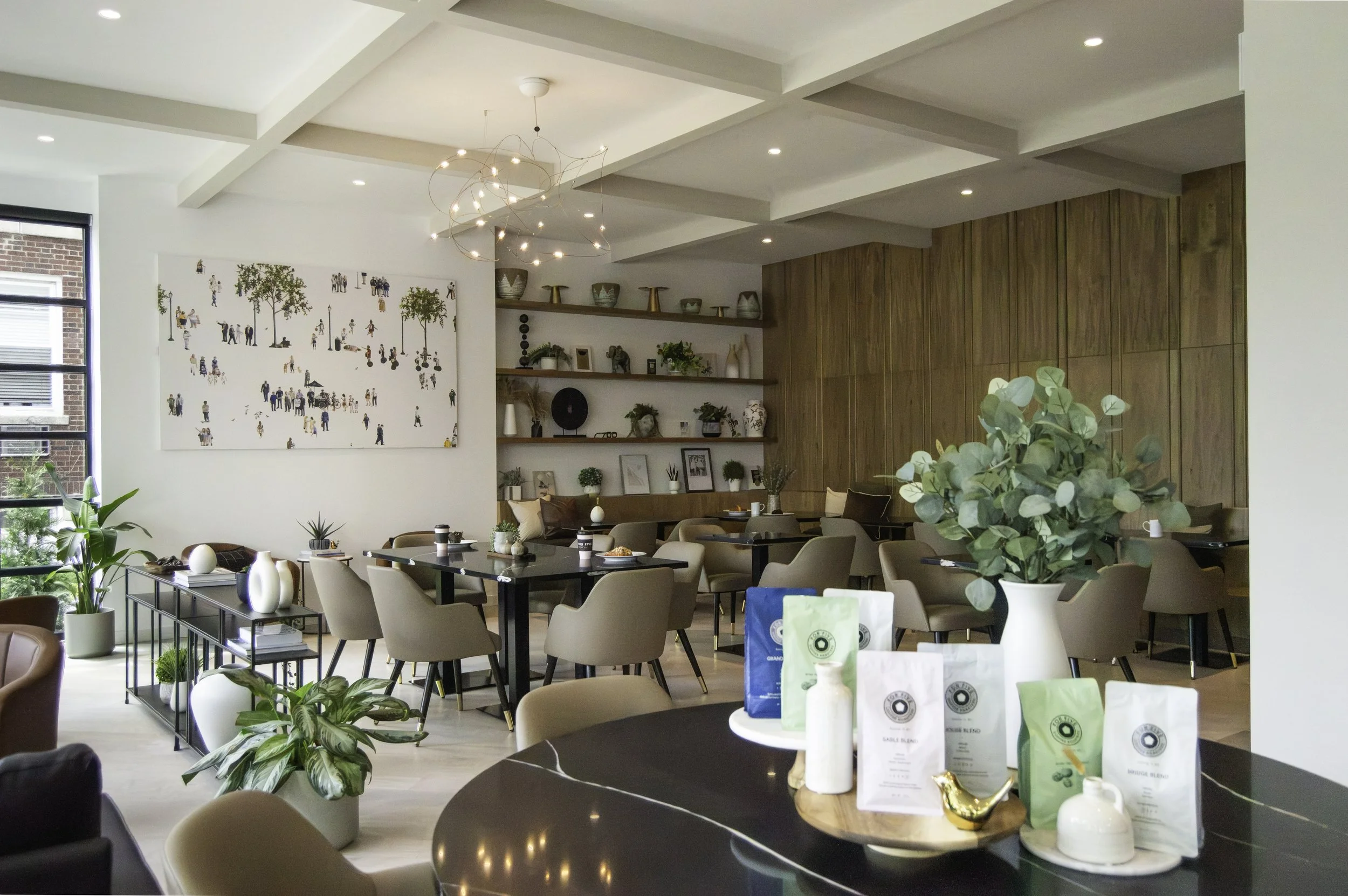 Dining area with a sculptural wire chandelier, gallery wall art, and floor-to-ceiling steel-framed windows at For Five Coffee Roasters, Garden City, NY