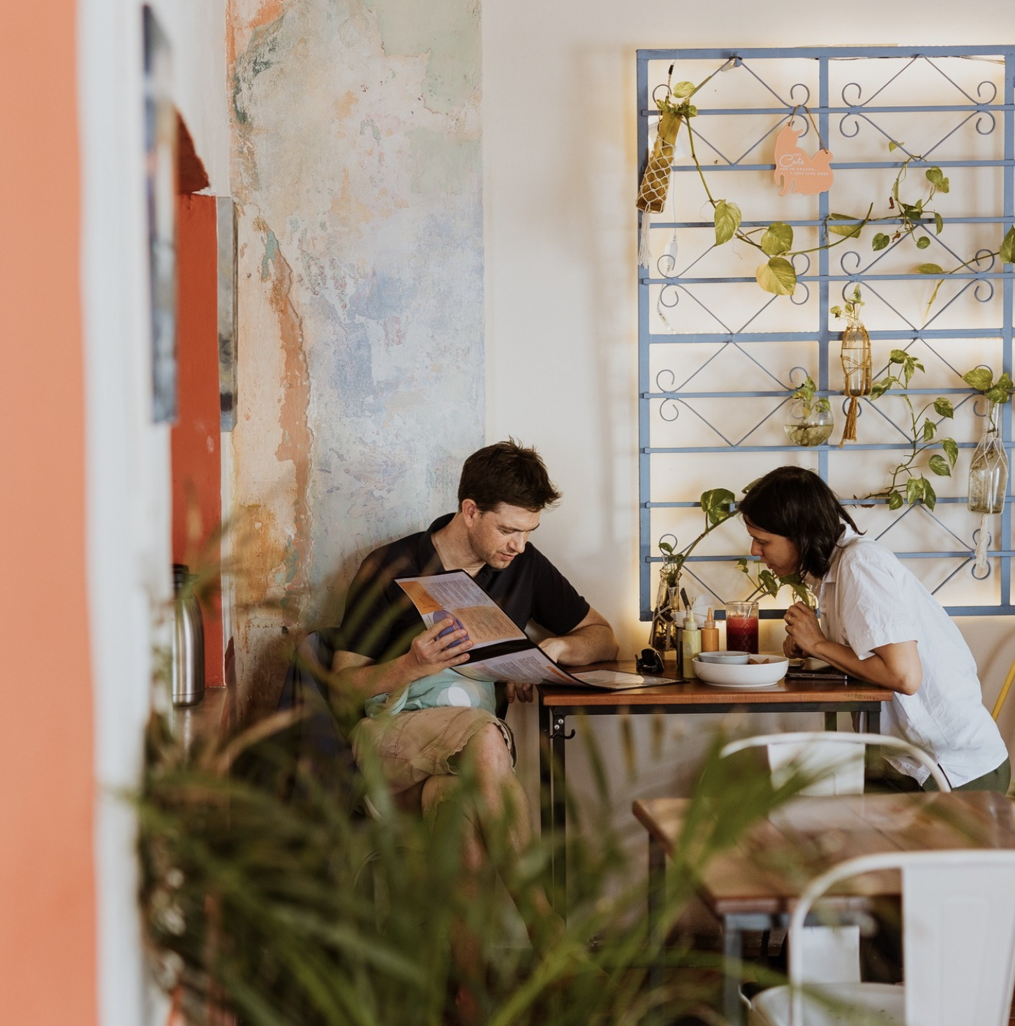 A man and woman sitting at a table in a cozy restaurant, looking at a menu and preparing to order food.