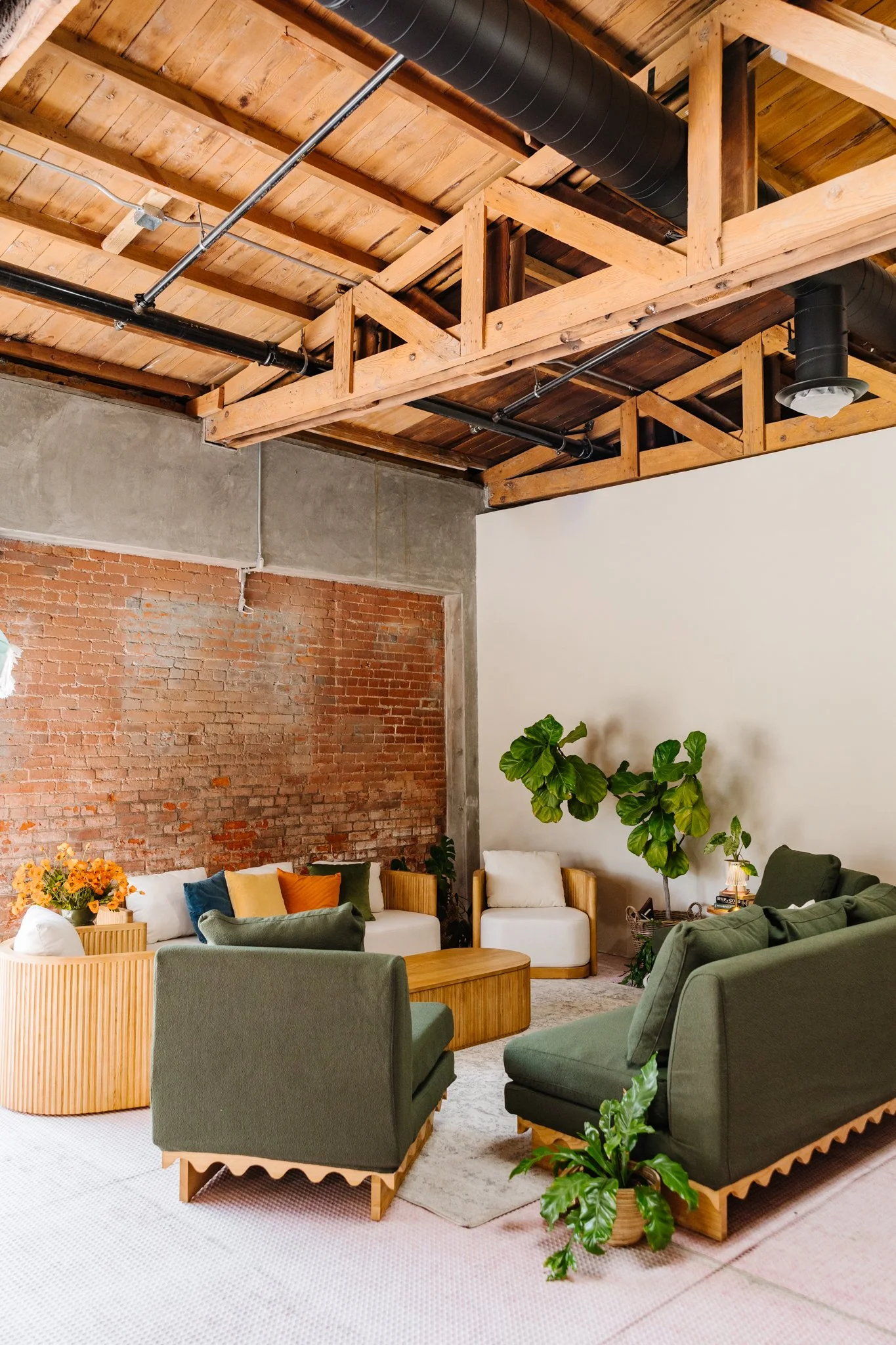 Original brick and wood beams tell the story of the building’s past, adding warmth, texture, and a sense of scale. Paired here with curated lounge furnishings available as add-on rentals, the space feels grounded, inviting, and ready for gathering.