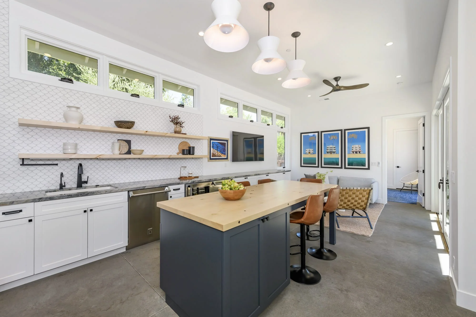Modern open-concept kitchen and living room with white cabinets, a wooden kitchen island, and minimalist decor.