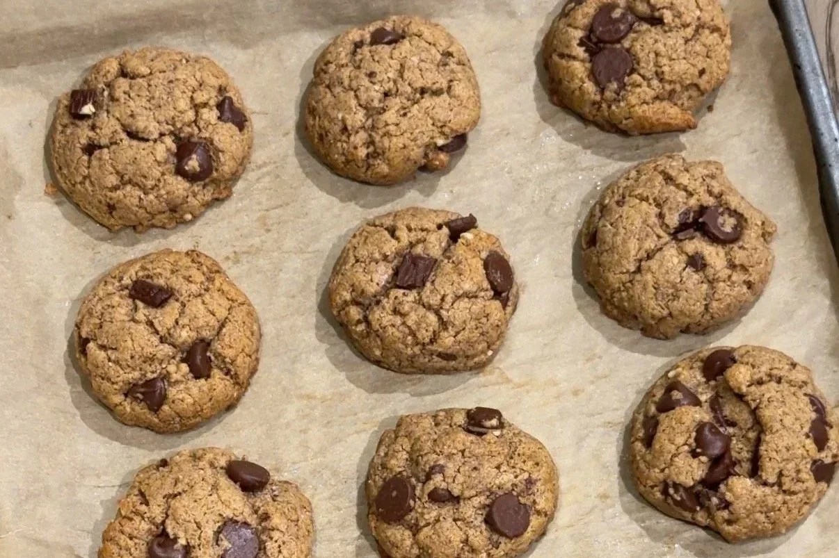 gluten free, flourless, dairy free, almond butter cookie with chocolate chips served on a baking sheet with parchment paper layered.