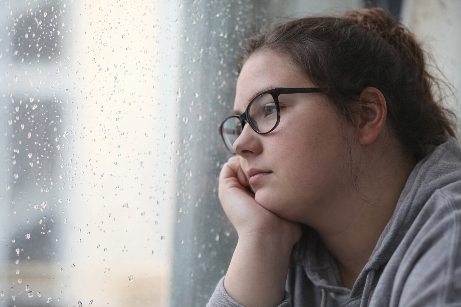Teen girl appearing withdrawn while looking out a window, symbolizing depression counselling at Watkins Counseling and Wellness in Smiths Falls.