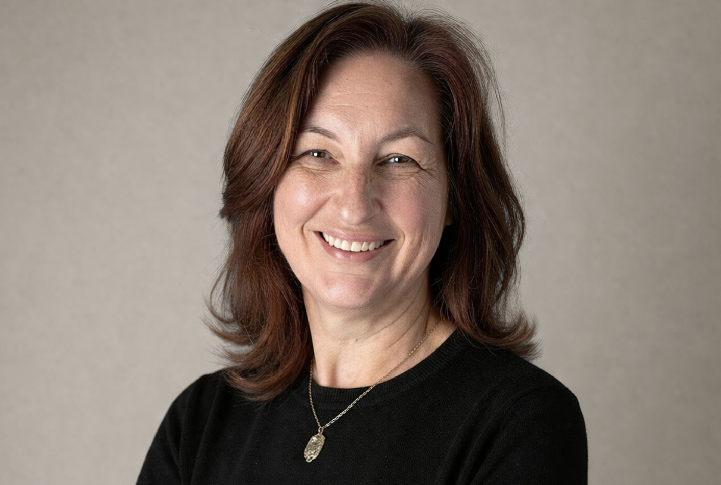 Professional black and white portrait of Nicola Wolters, Registered Psychotherapist (Qualifying) at Watkins Counselling & Wellness, smiling warmly against a soft neutral studio background.