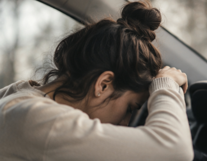 Woman sitting in car feeling emotionally overwhelmed after a motor vehicle accident