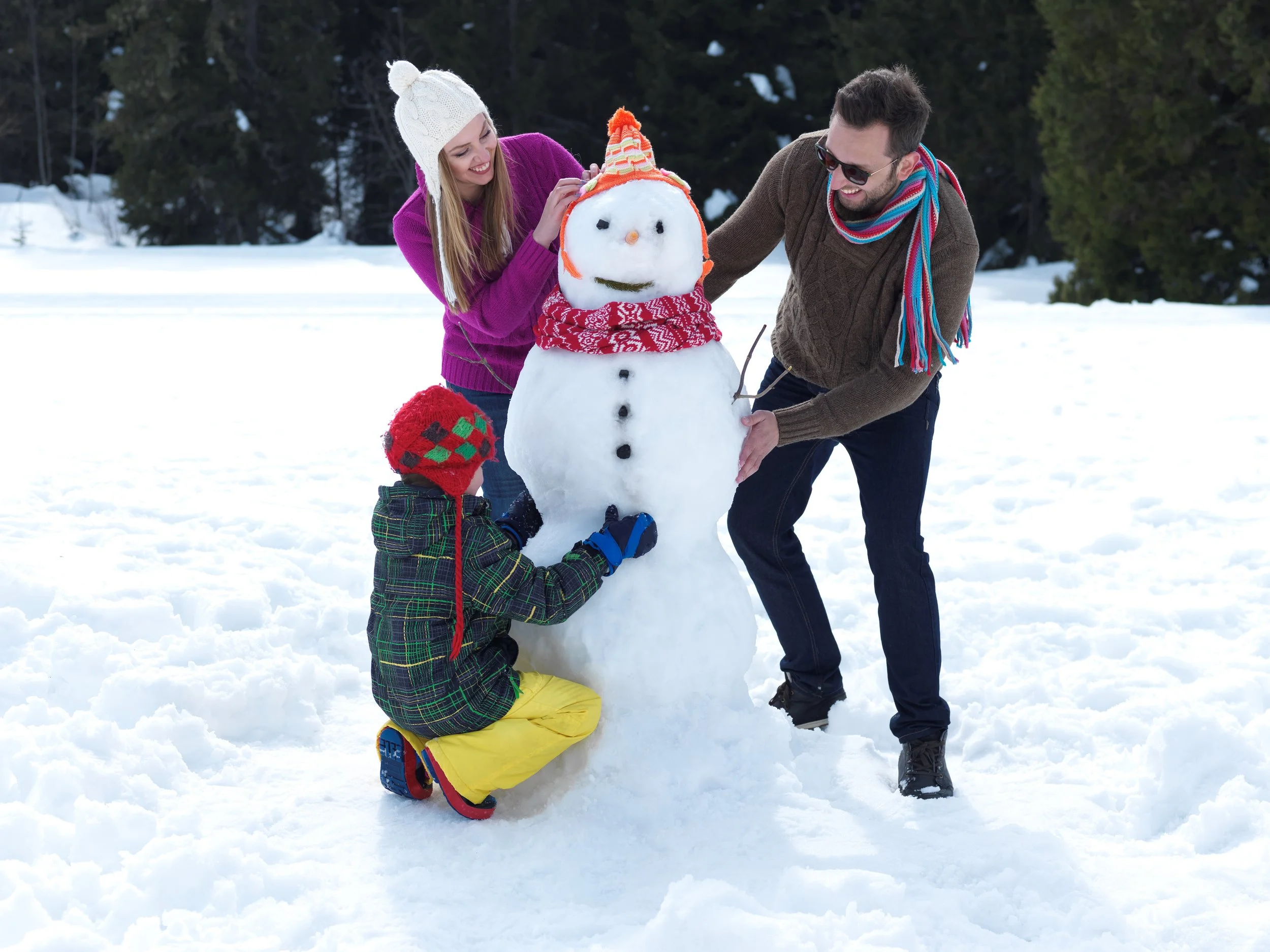 family building a snowman together in winter, symbolizing connection and attachment-focused therapy in smiths falls, ontario.
