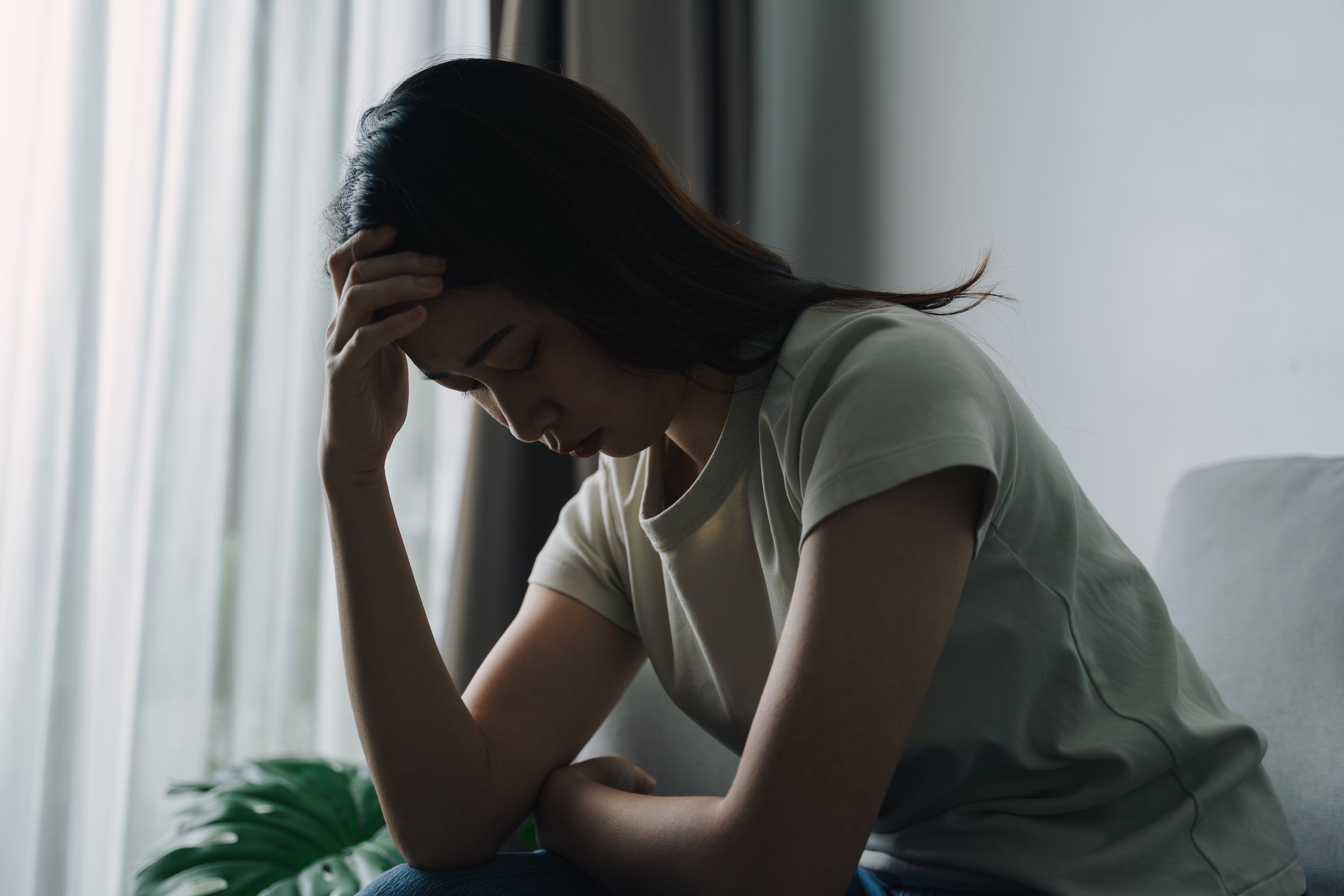 woman sitting on a couch with her head in her hand, representing depression and emotional overwhelm, reflecting therapy support in smiths falls, ontario.