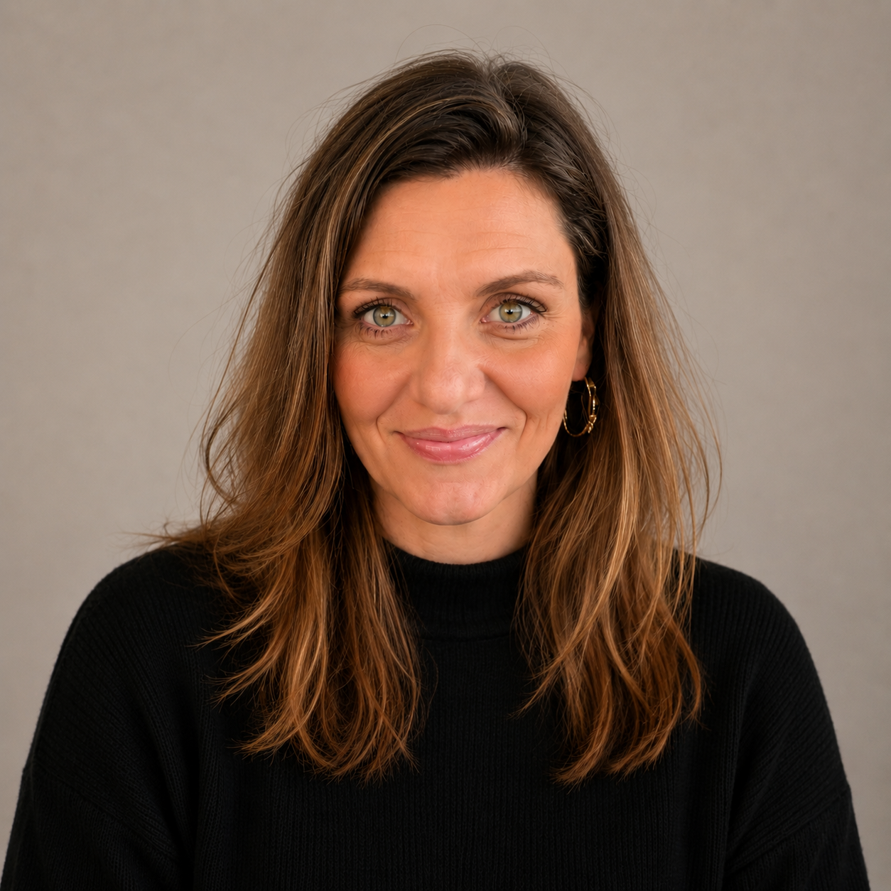 Joe-Ann Watkins, Registered Psychotherapist, with long brown hair and green eyes, smiling, wearing a black turtleneck, standing against a plain light background.