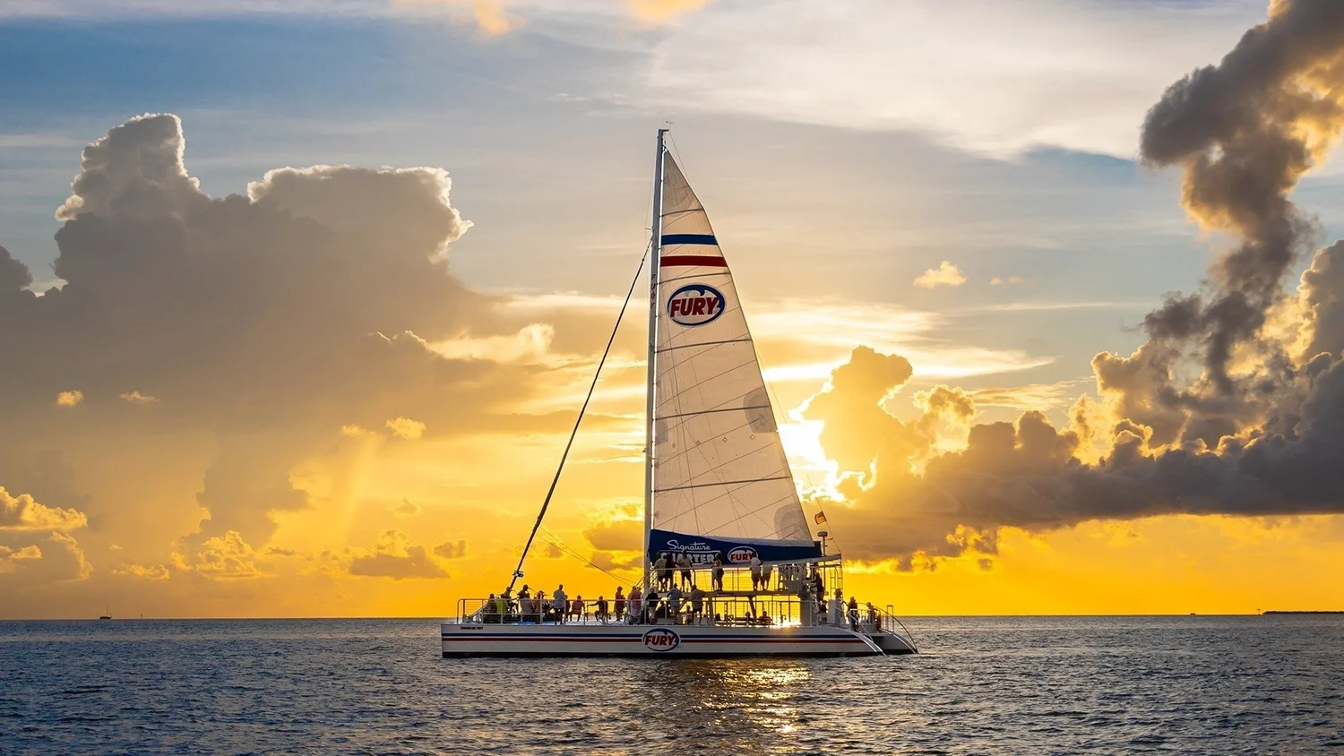 Fury catamaran sailing beneath a golden Key West sunset