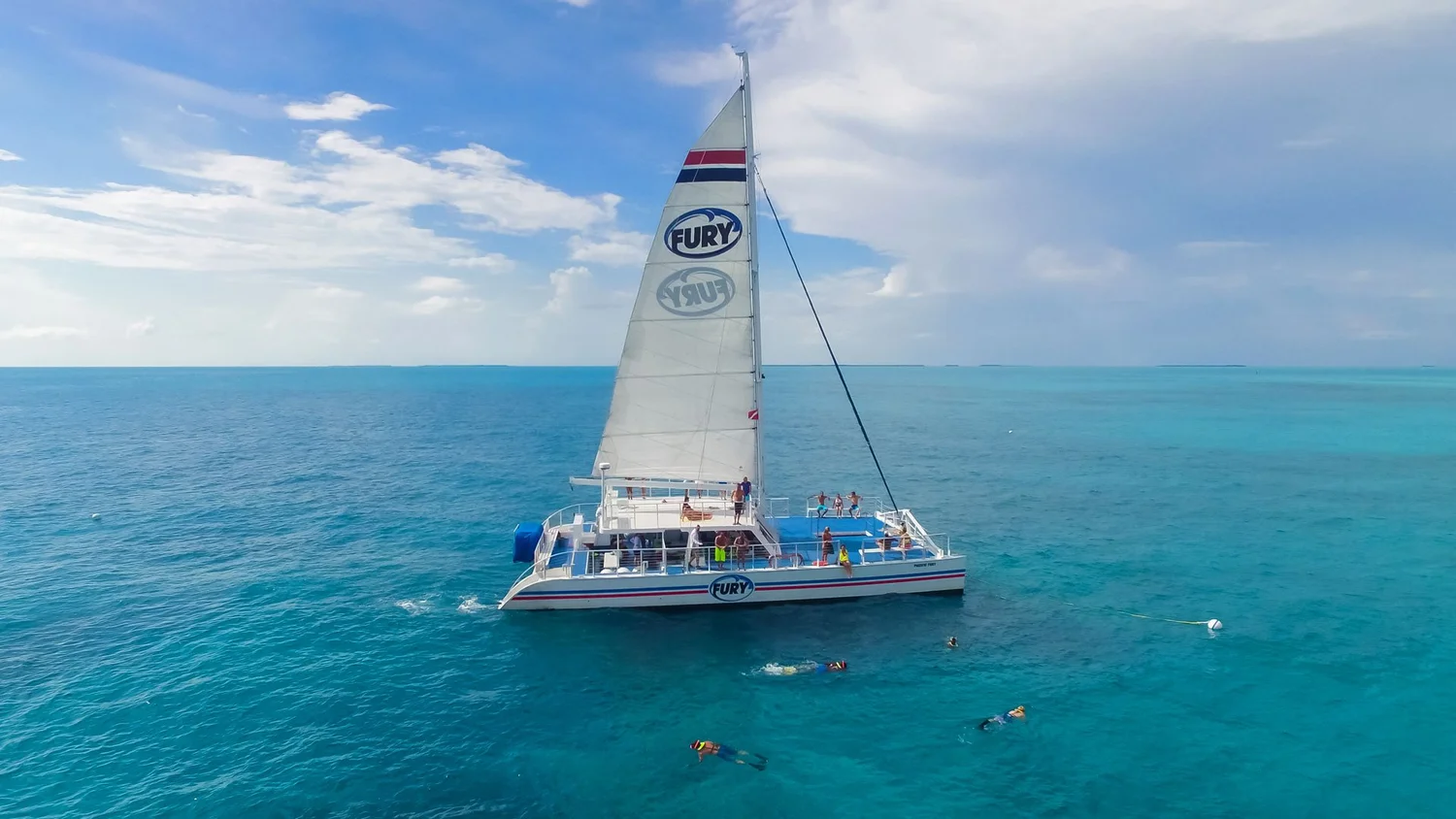 Snorkelers beside a Fury catamaran in turquoise water